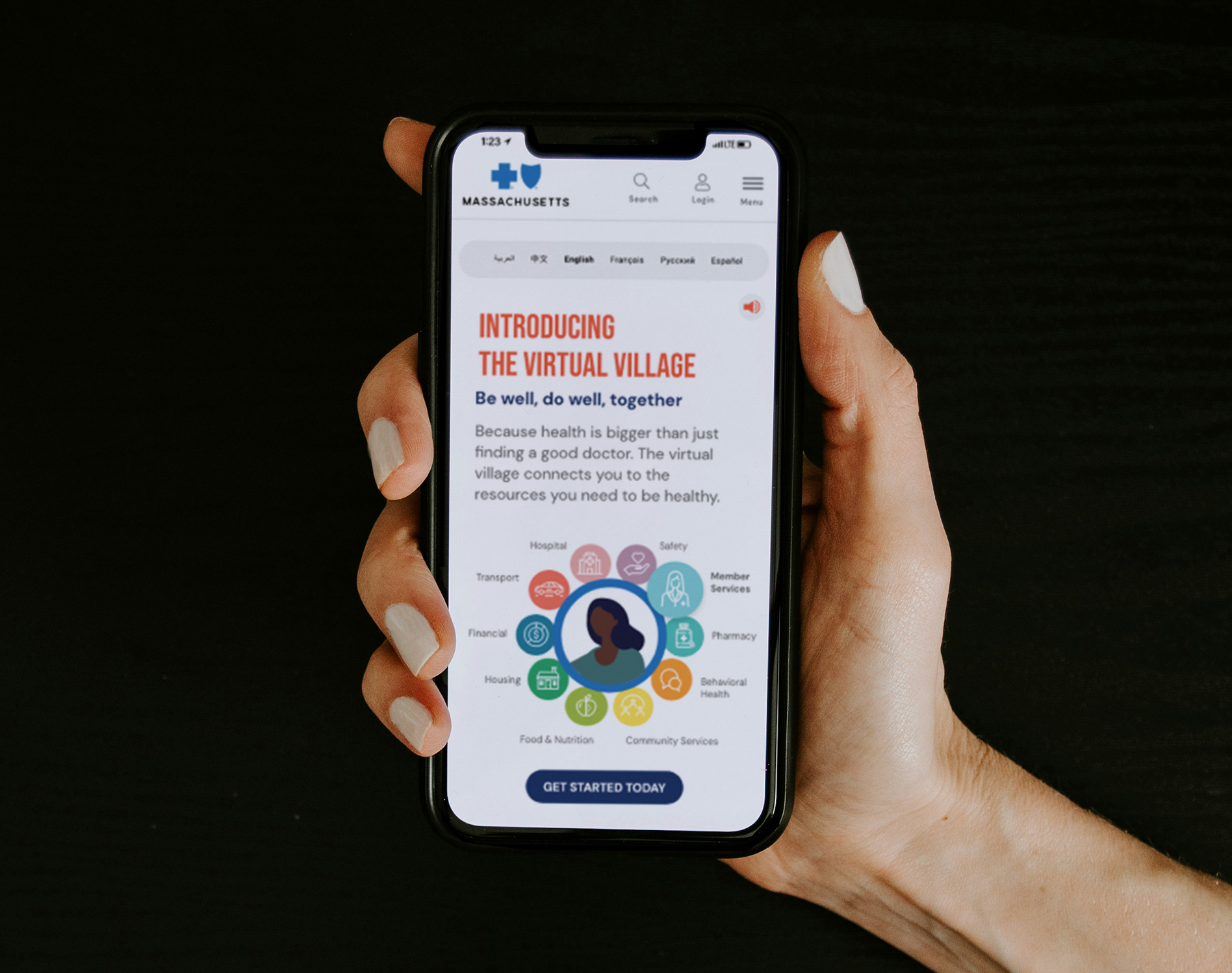 A person holding a smartphone displaying the virtual village website for health resources in Massachusetts