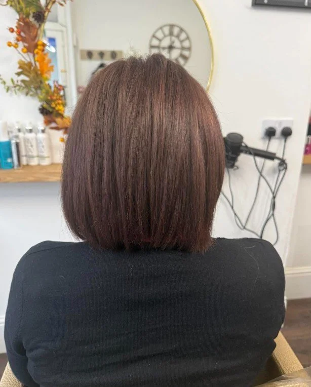 Back view of a woman with a short, straight bob haircut in a salon