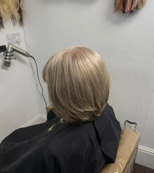 Person with light blonde hair in a short, layered bob sitting in a salon chair.