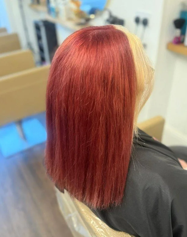 Person with straight, shoulder-length hair dyed in a vibrant red color.