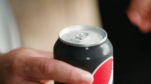 Close-up of a hand opening a can of soda.