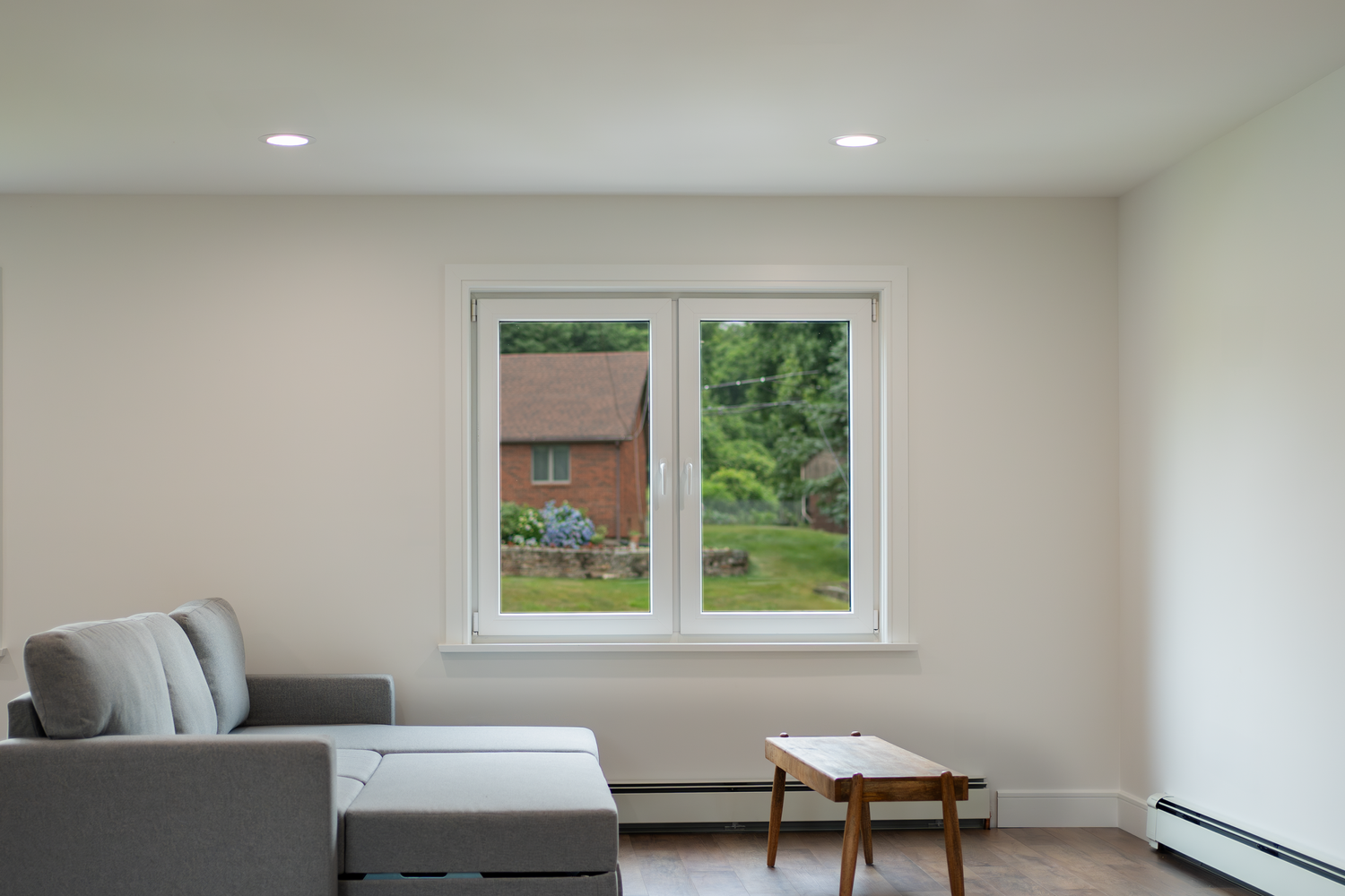 Minimalist living room with a GALAA tilt-and-turn window showcasing an outdoor view