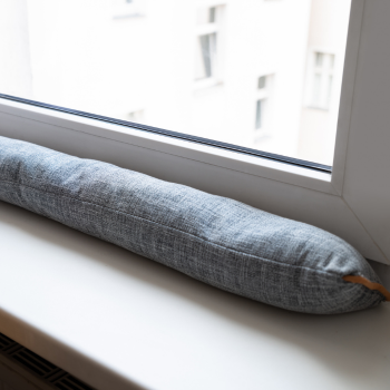 Fabric draft stopper laid along a window sill to block air leaking past the sash