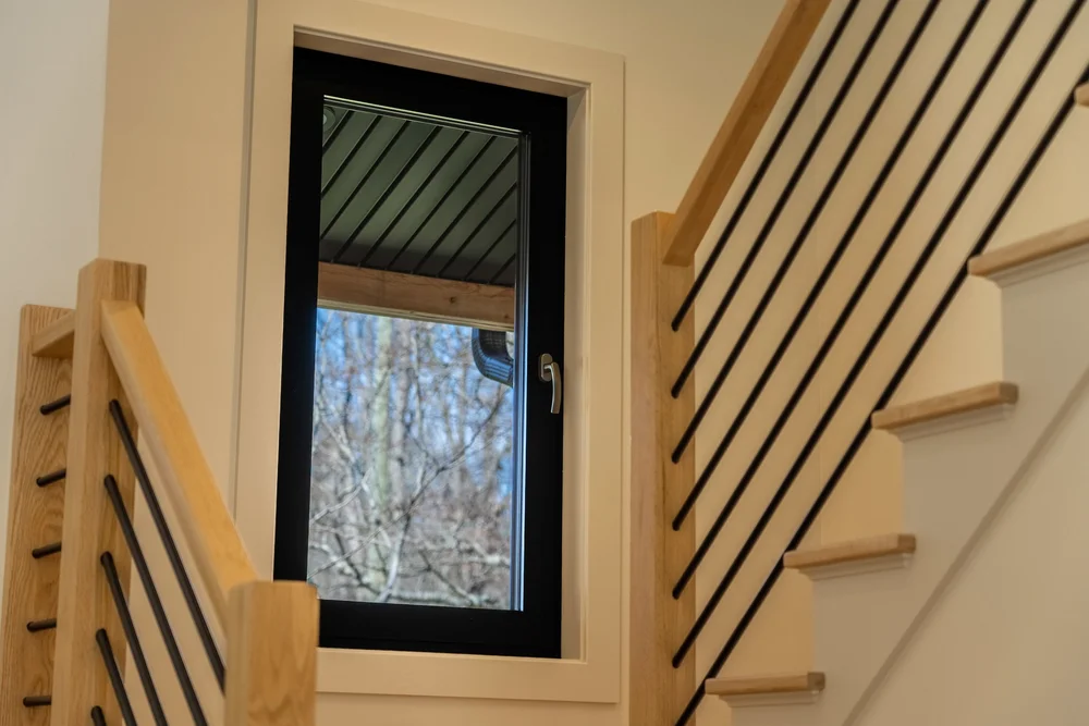 Stairwell window with a black frame overlooking trees