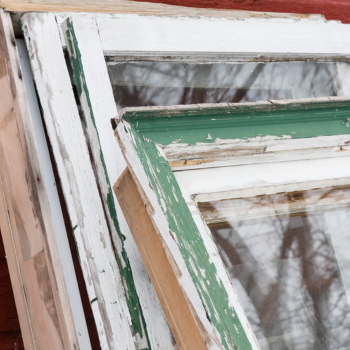 Peeling paint and rotting wood on an old window frame and sash