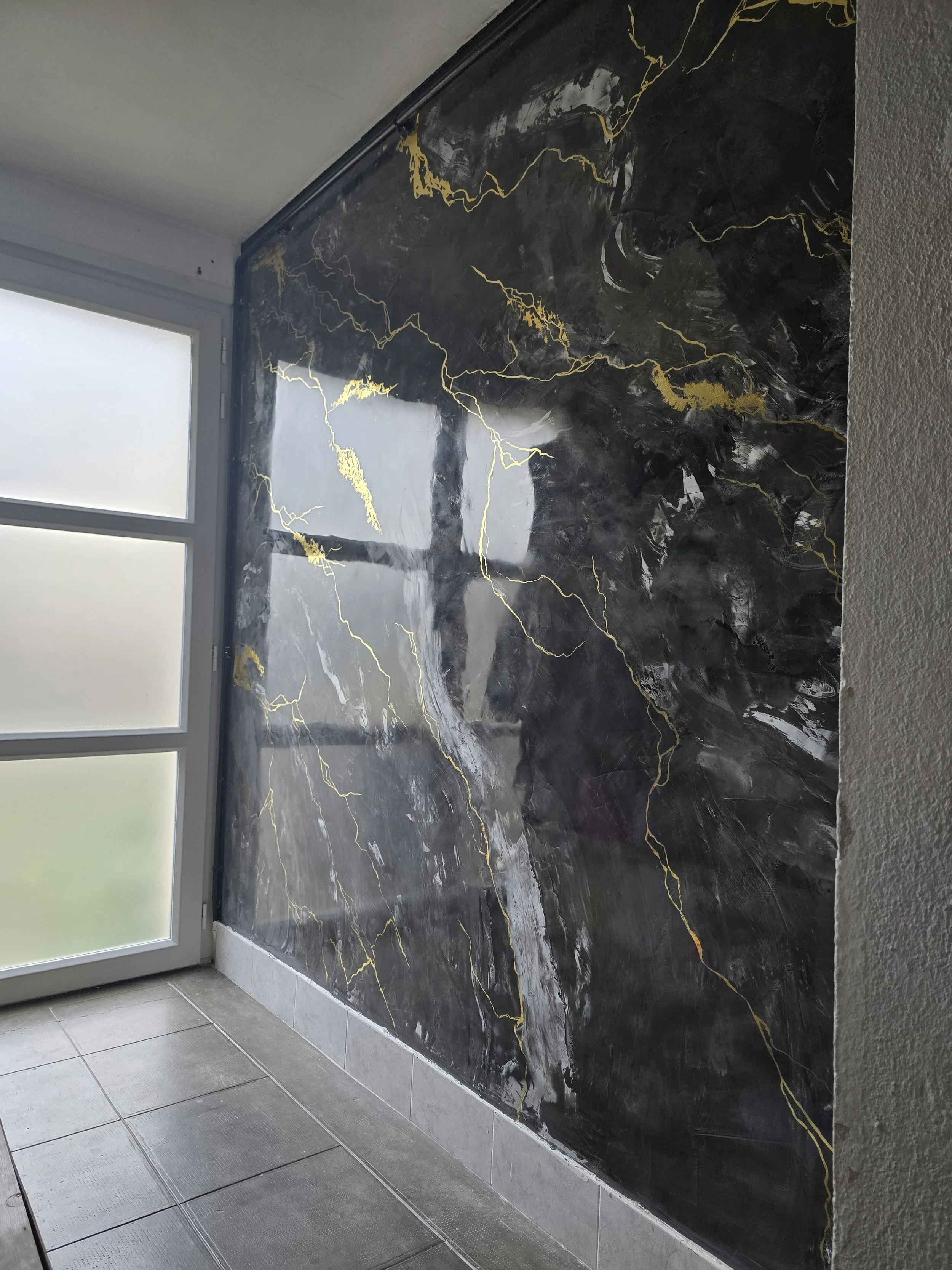 Mur enduit marbré noir veines dorées - sas d'entrée réalisé par Opus Aurea Albi