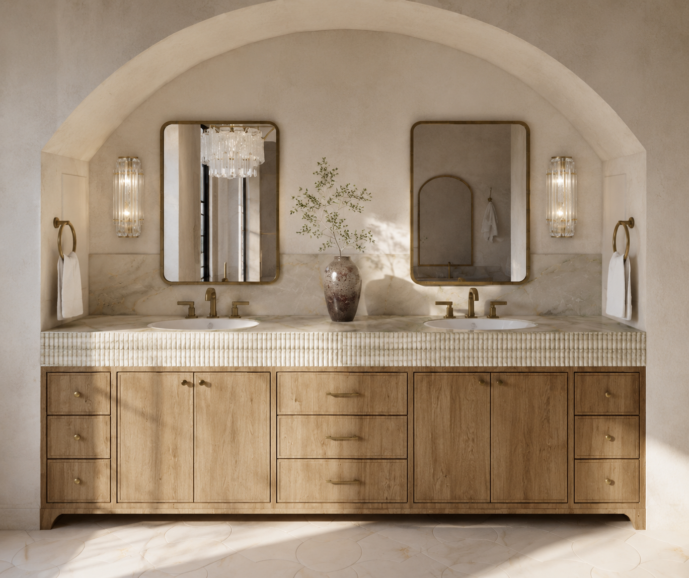 Double vanity bathroom with two mirrors, two sinks with brass fixtures, a vase with green branches, and decorative wall sconces