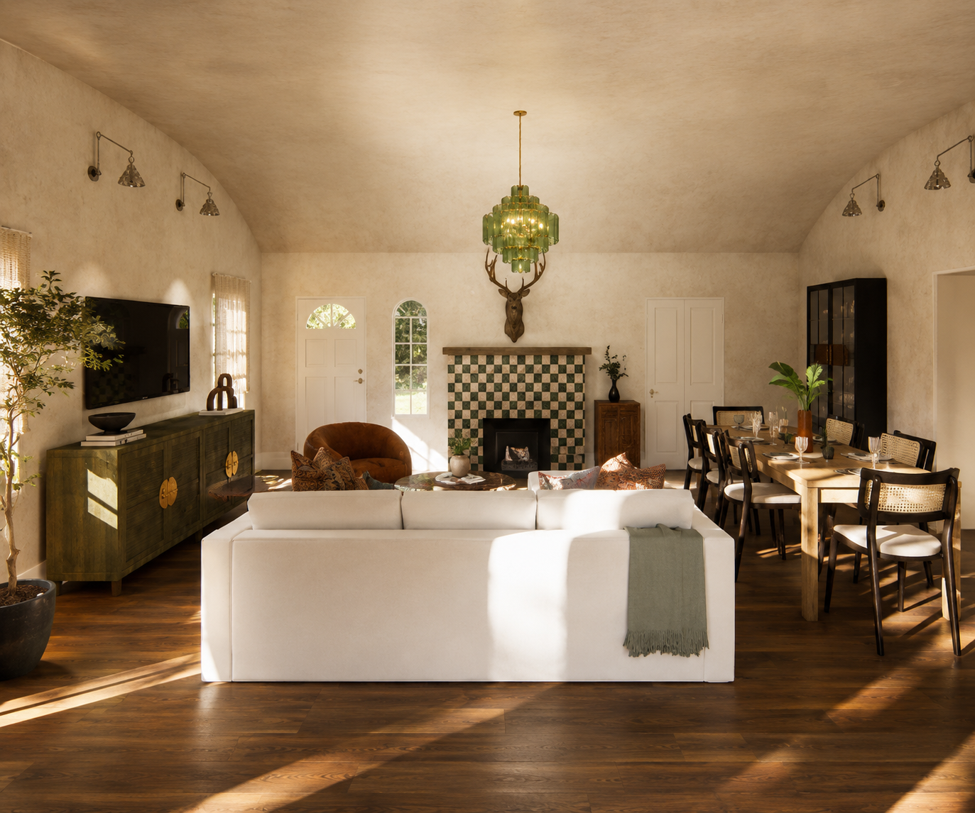 Living room with a white sofa, fireplace with green and white tiles, a chandelier with green accents, a dining table with chairs, potted plants, and decorative items, lit by natural sunlight.