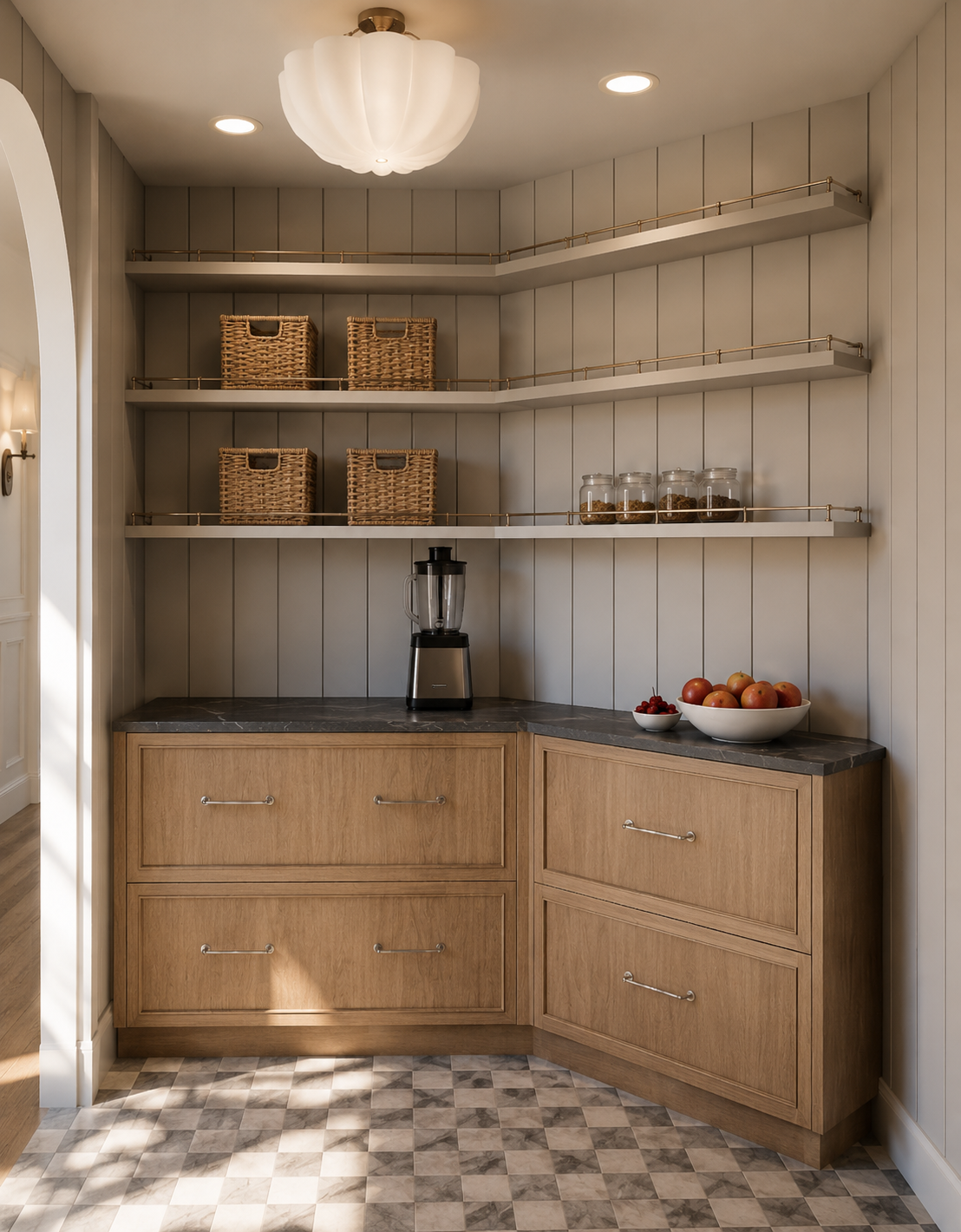 Kitchen corner with wooden cabinets, a black blender on a gray countertop, open shelves with wicker baskets and glass jars, a bowl of apples and cherries, and a ceiling light fixture.