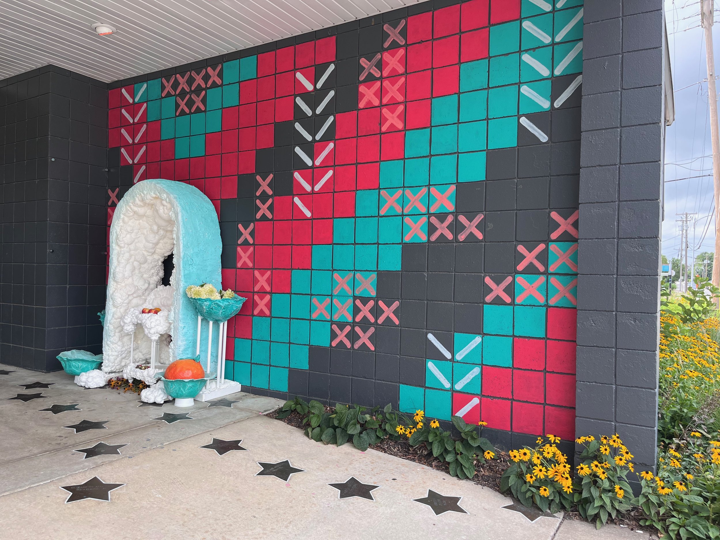 An altar in front of a mural lead to the entrance of a building
