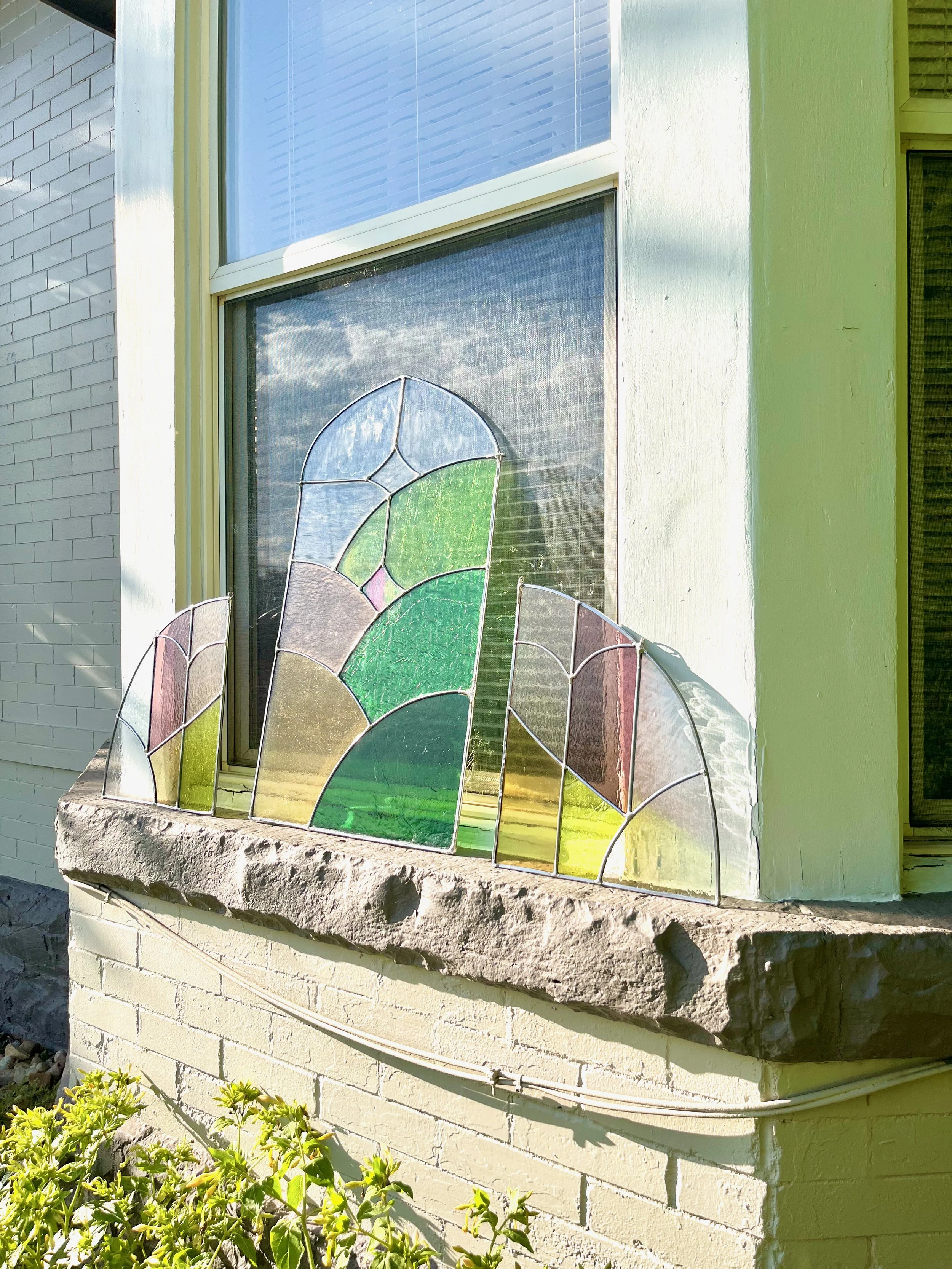Arched stained glass panels resting on window sill