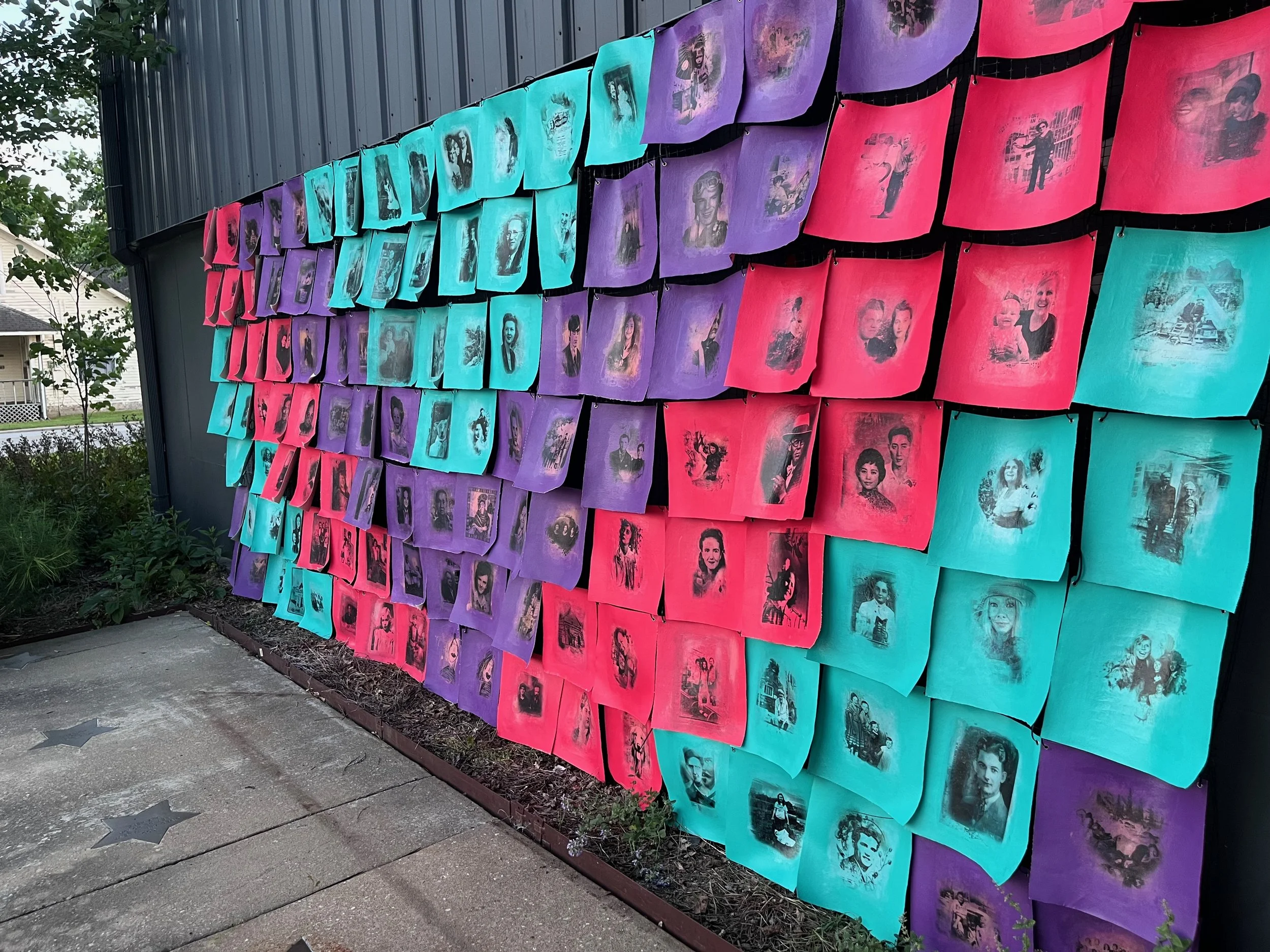 Photos of ancestors wrap an exterior, outdoor building wall