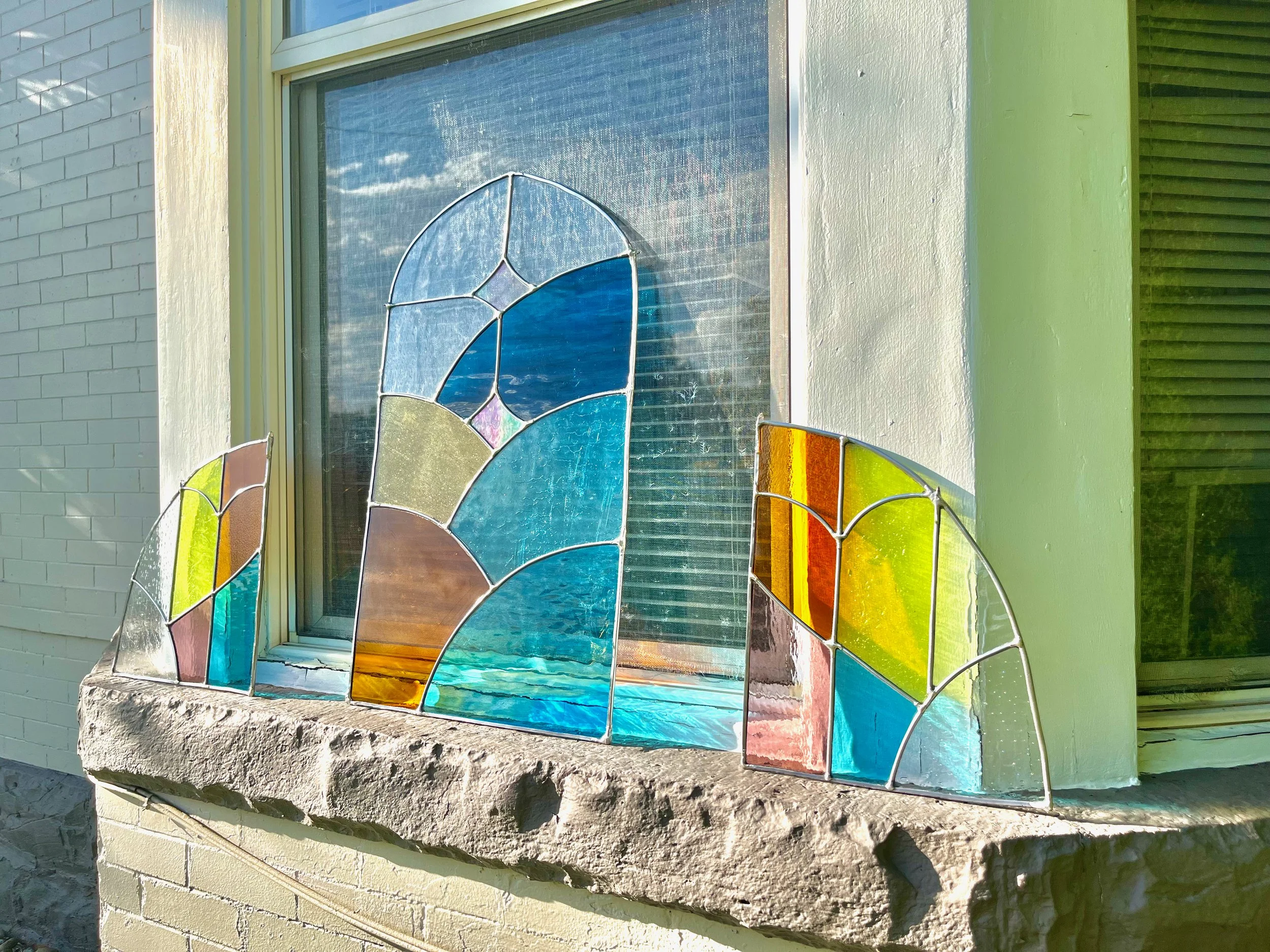 Arched stained glass panels resting on window sill