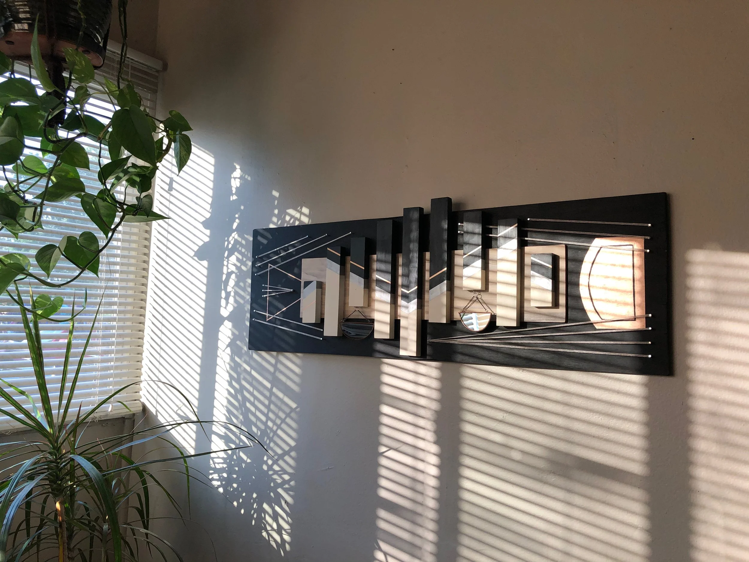 Geometric wood and stained glass sculpture hanging on wall