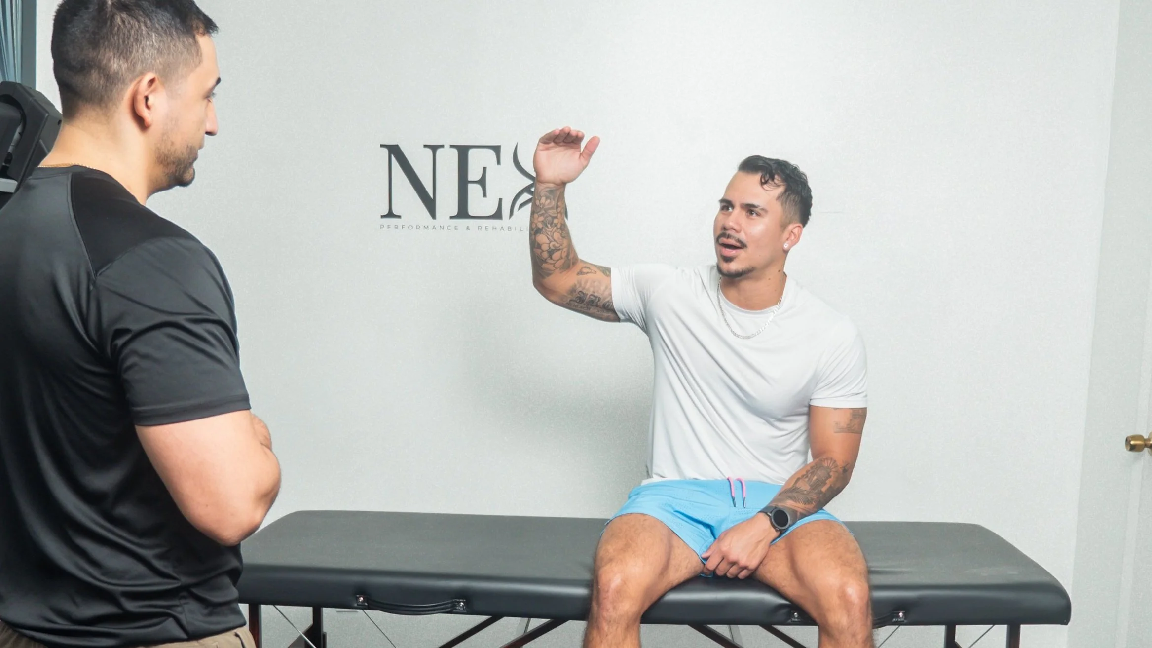 dr. Felipe Castro performing an evaluation with a client carefully listening to discover cause of pain in an athlete in his physical therapy studio in north miami beach