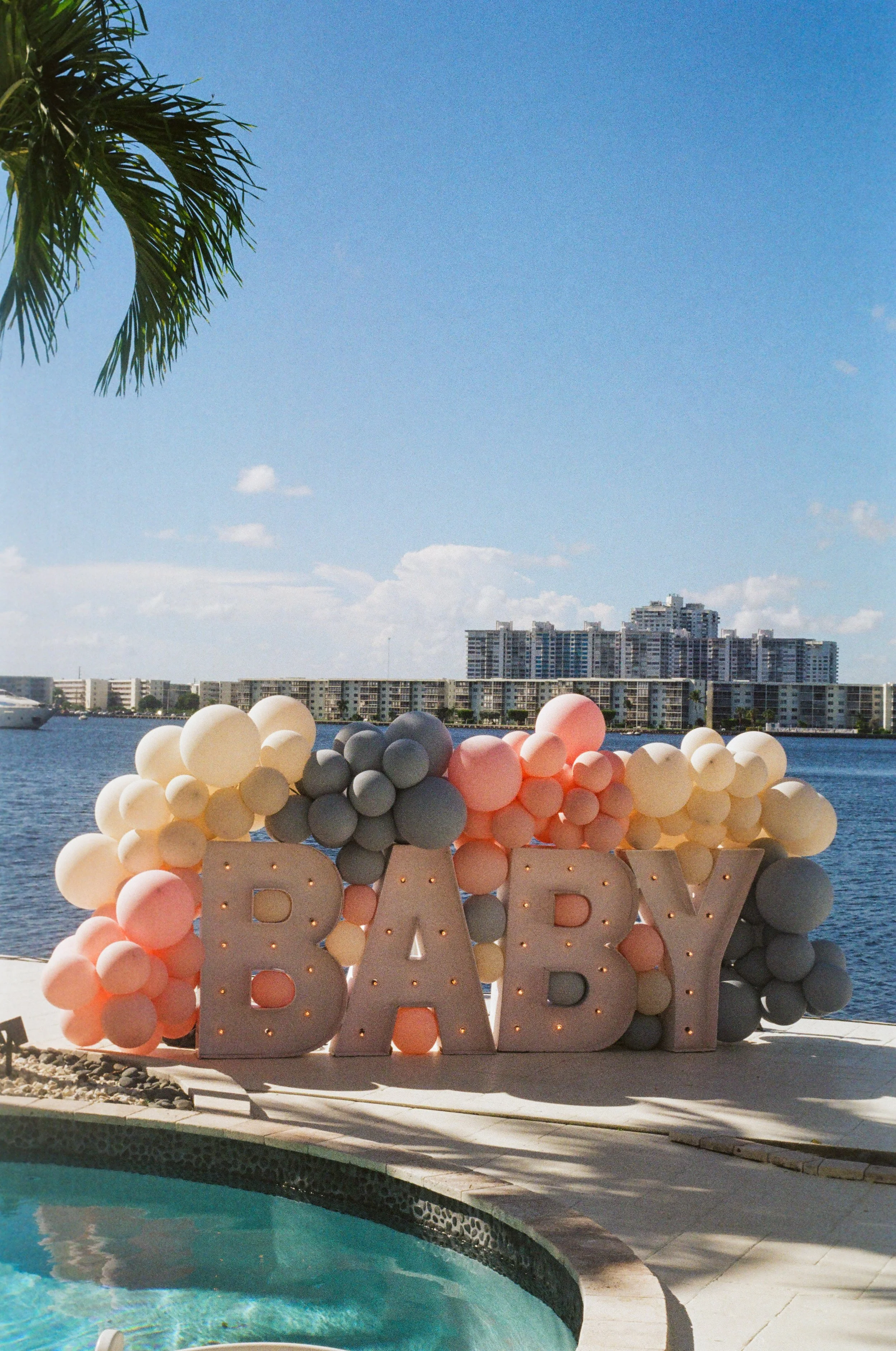 Decorative balloon arrangement next to a pool with a cityscape and water in the background