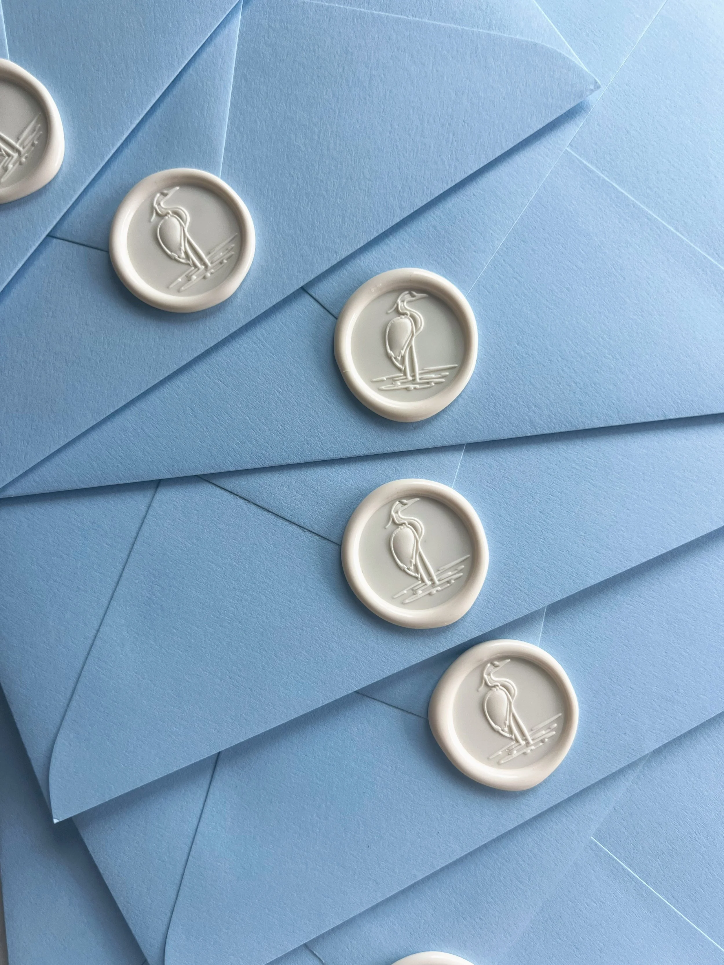 Light blue envelopes sealed with white wax seals featuring a heron engraving.