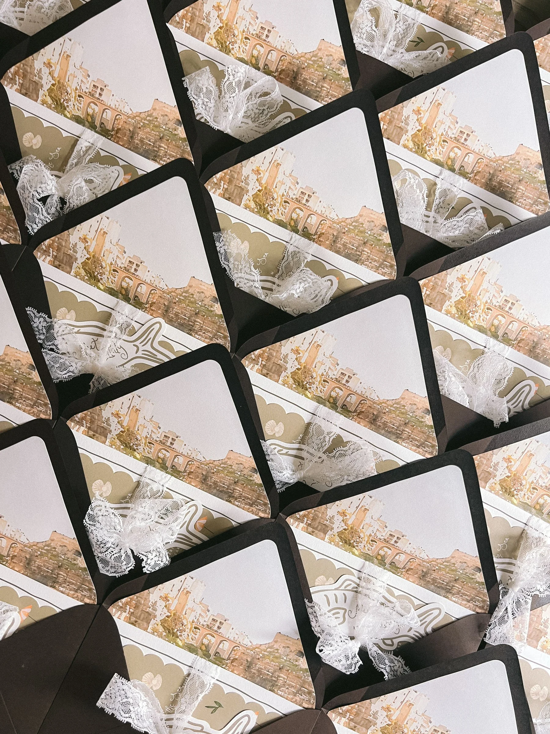 Multiple gift boxes decorated with cityscape illustrations and white lace ribbons.