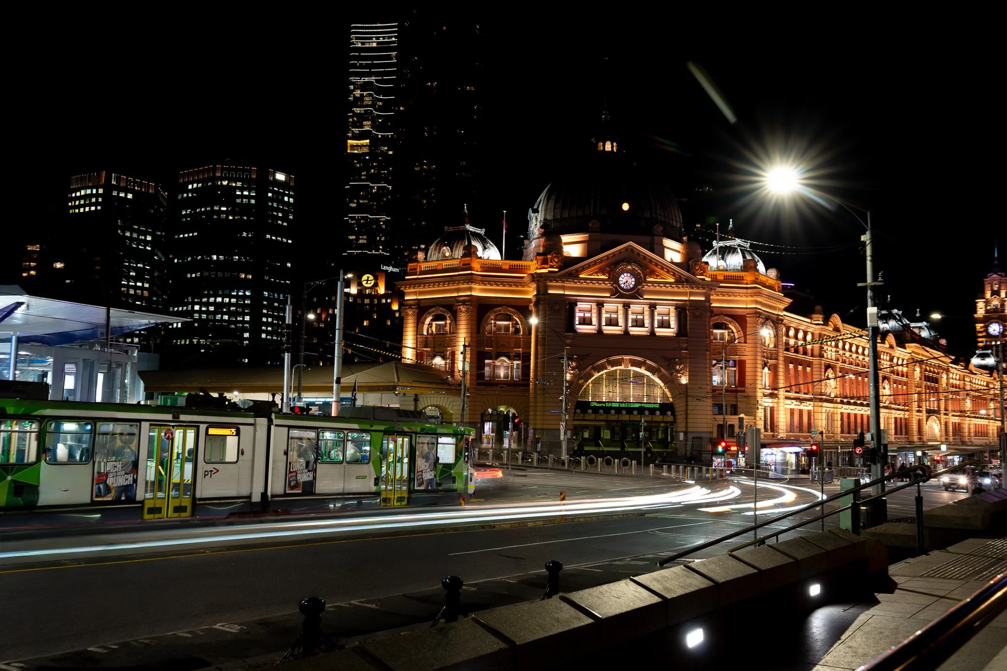 Flinders Street Station at night with the passing car light trailing