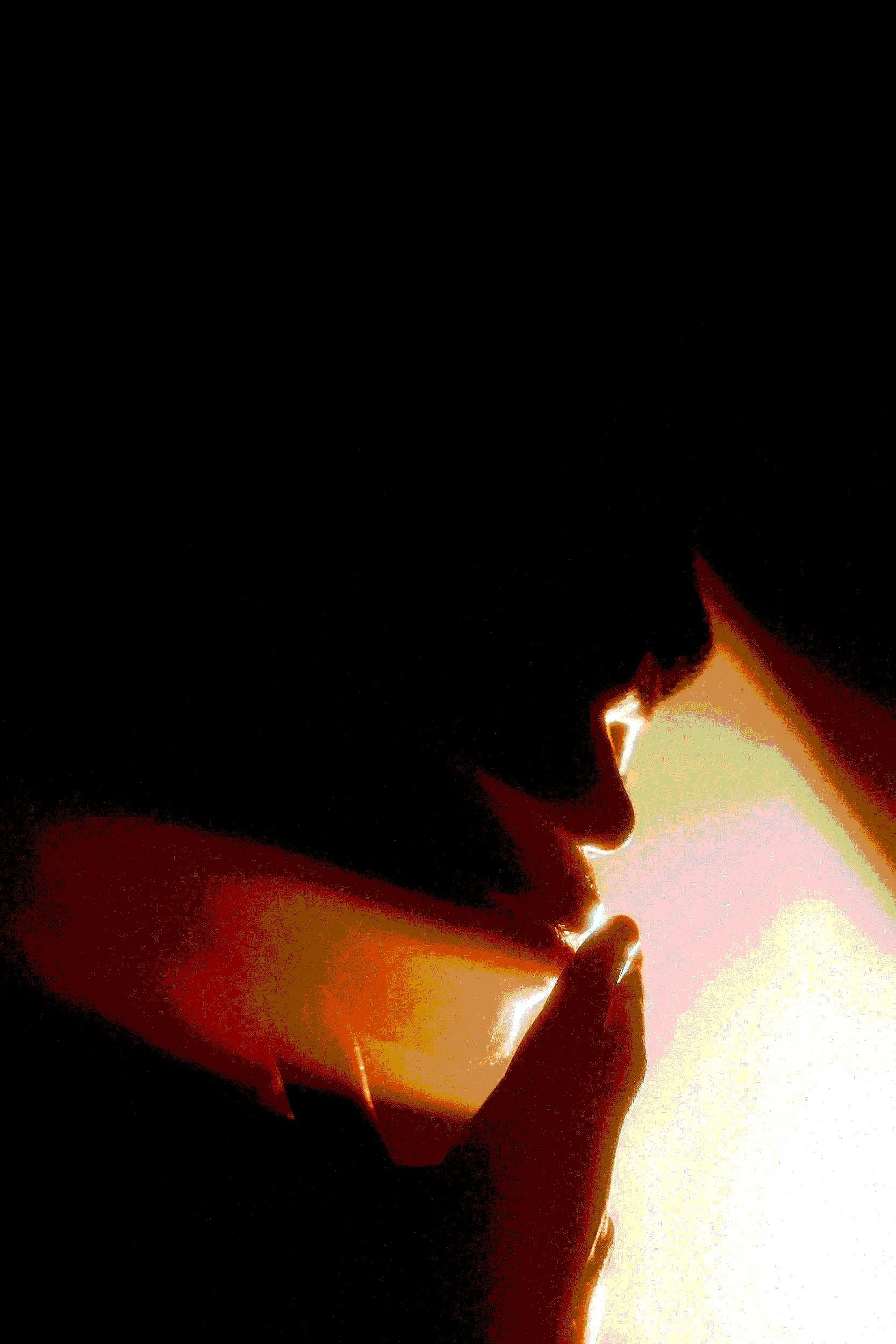 Retrato de uma pessoa com cabelo escuro, de perfil, tocando os lábios com um dedo, com luz suave ao fundo.