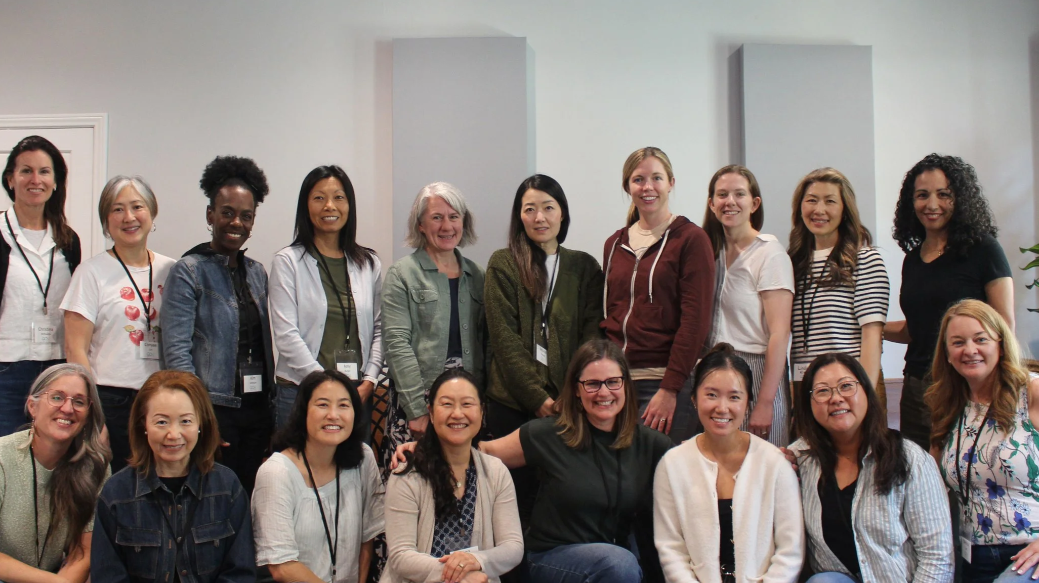 A diverse group of women smiling and posing for a group photo at an indoor event.