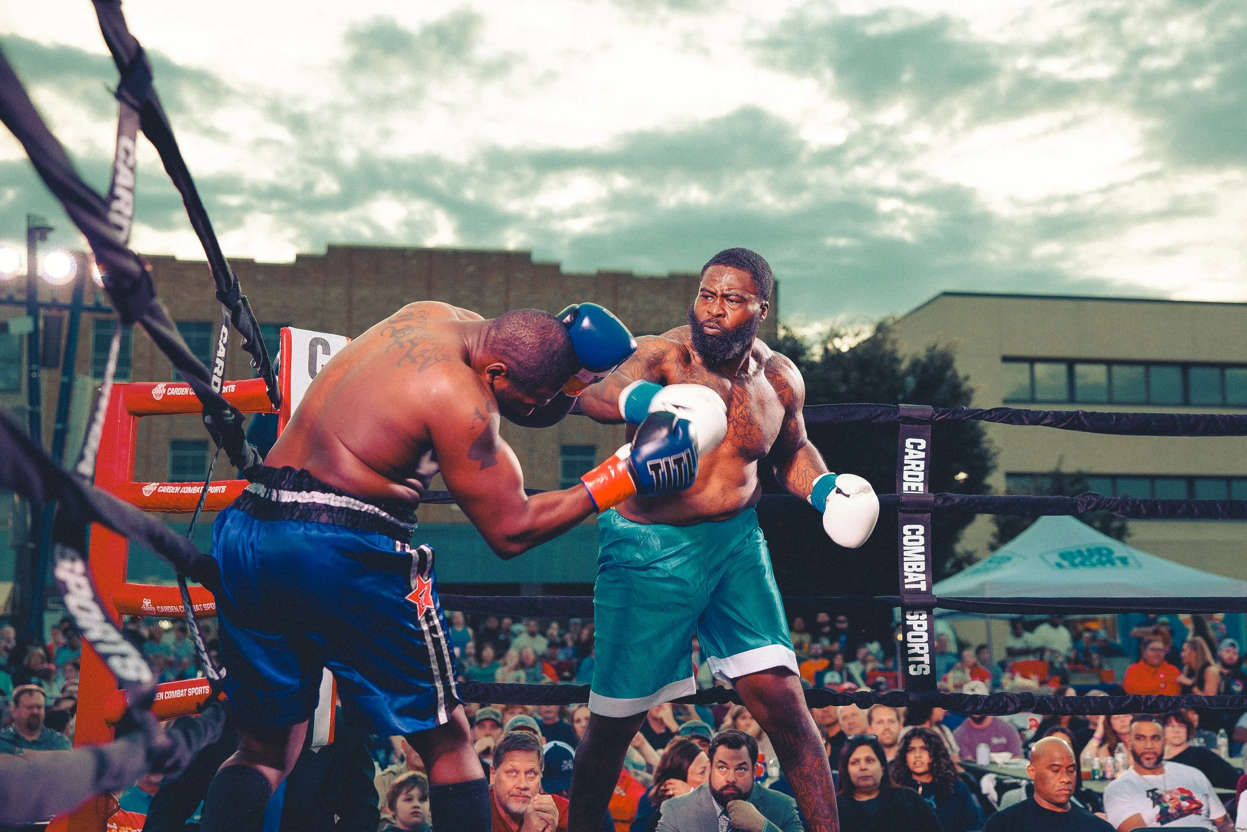 Two shirtless men boxing in an outdoor ring with a crowd watching, one throwing a punch at the other. Shot at Evergy Plaza in Topeka, Kansas. 