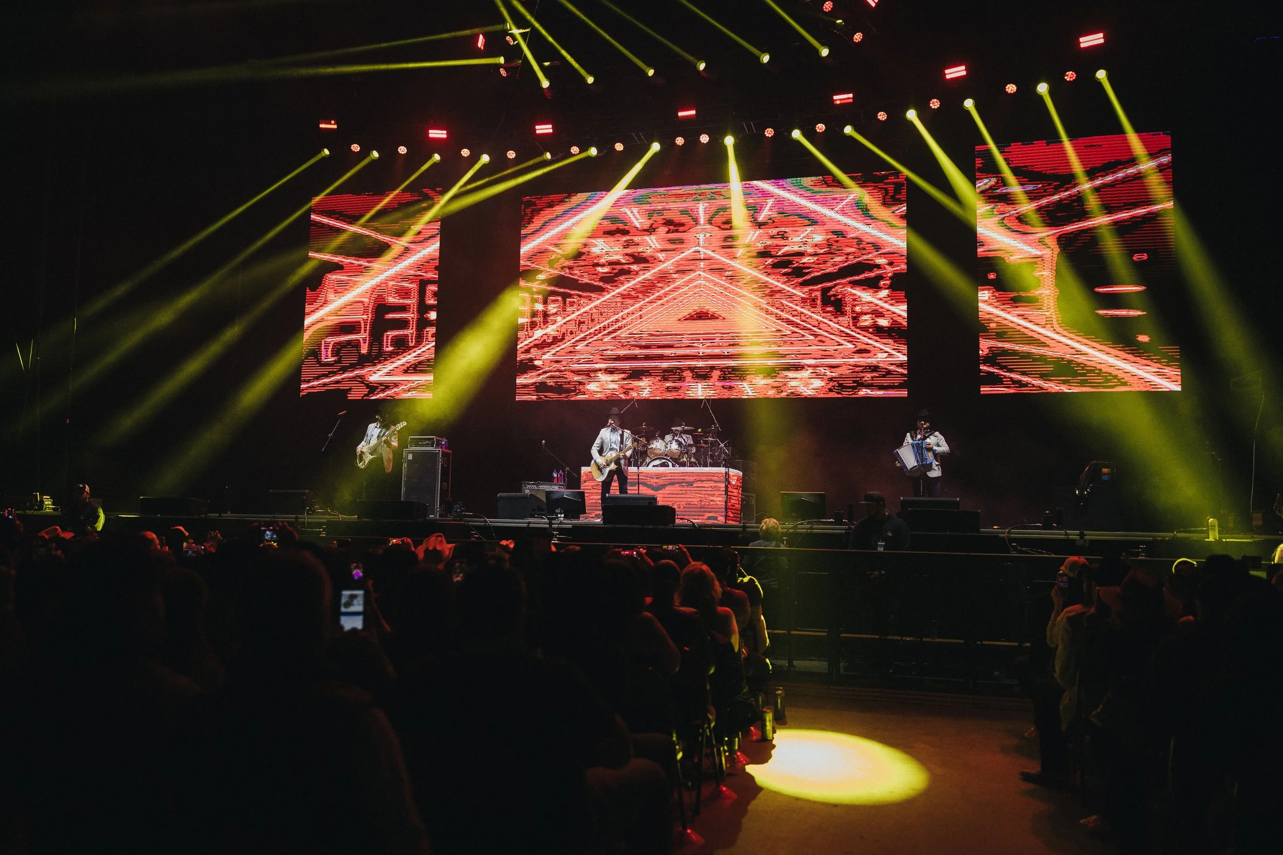 A band performing on stage with colorful lighting and a digital backdrop at a concert. Los Tucanes de Tijuana Stormont Vail Event Center Topeka, Kansas. 