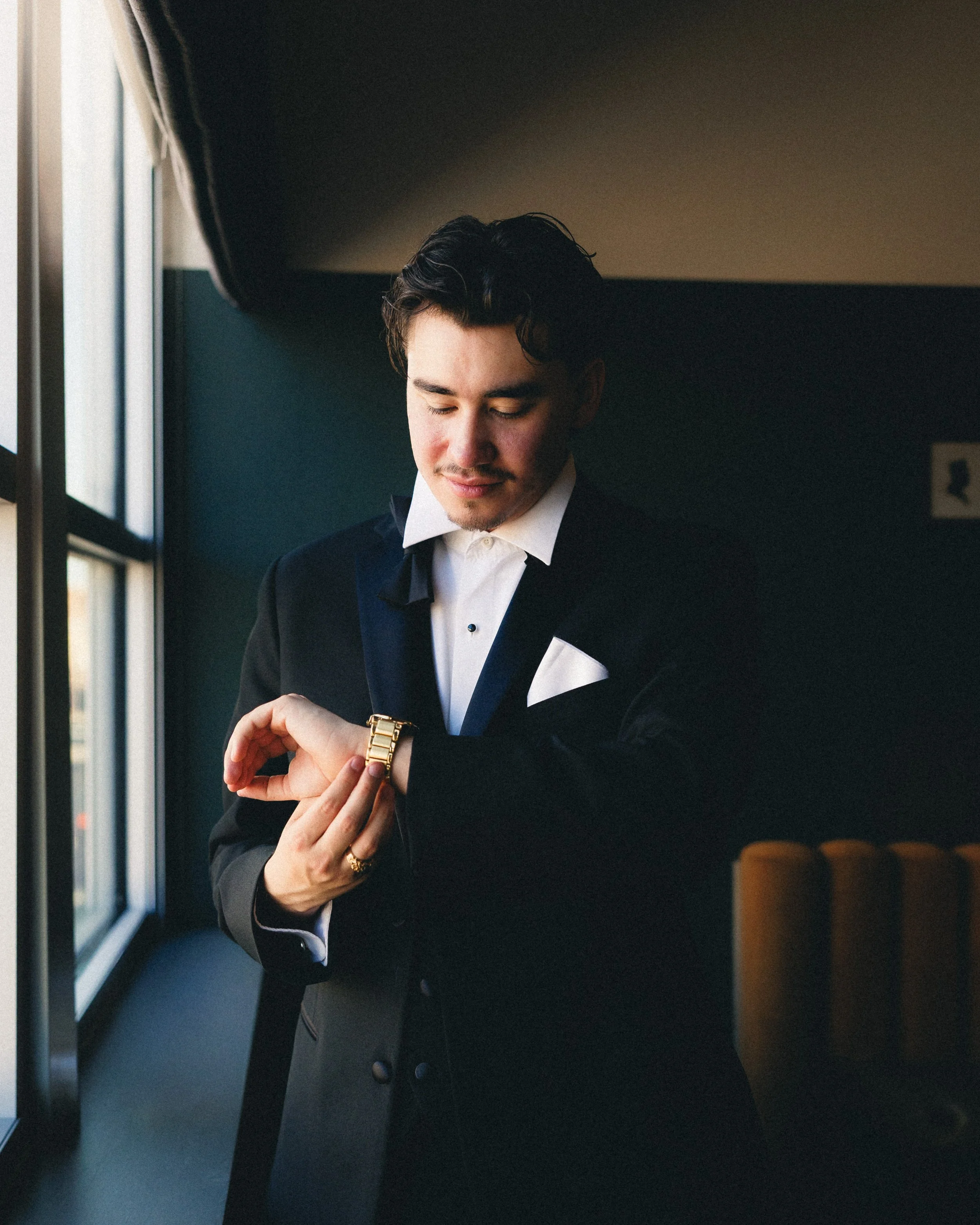 A man in a tuxedo looking at his wristwatch near a window. Shot at Cyrus Hotel in Topeka, Kansas.