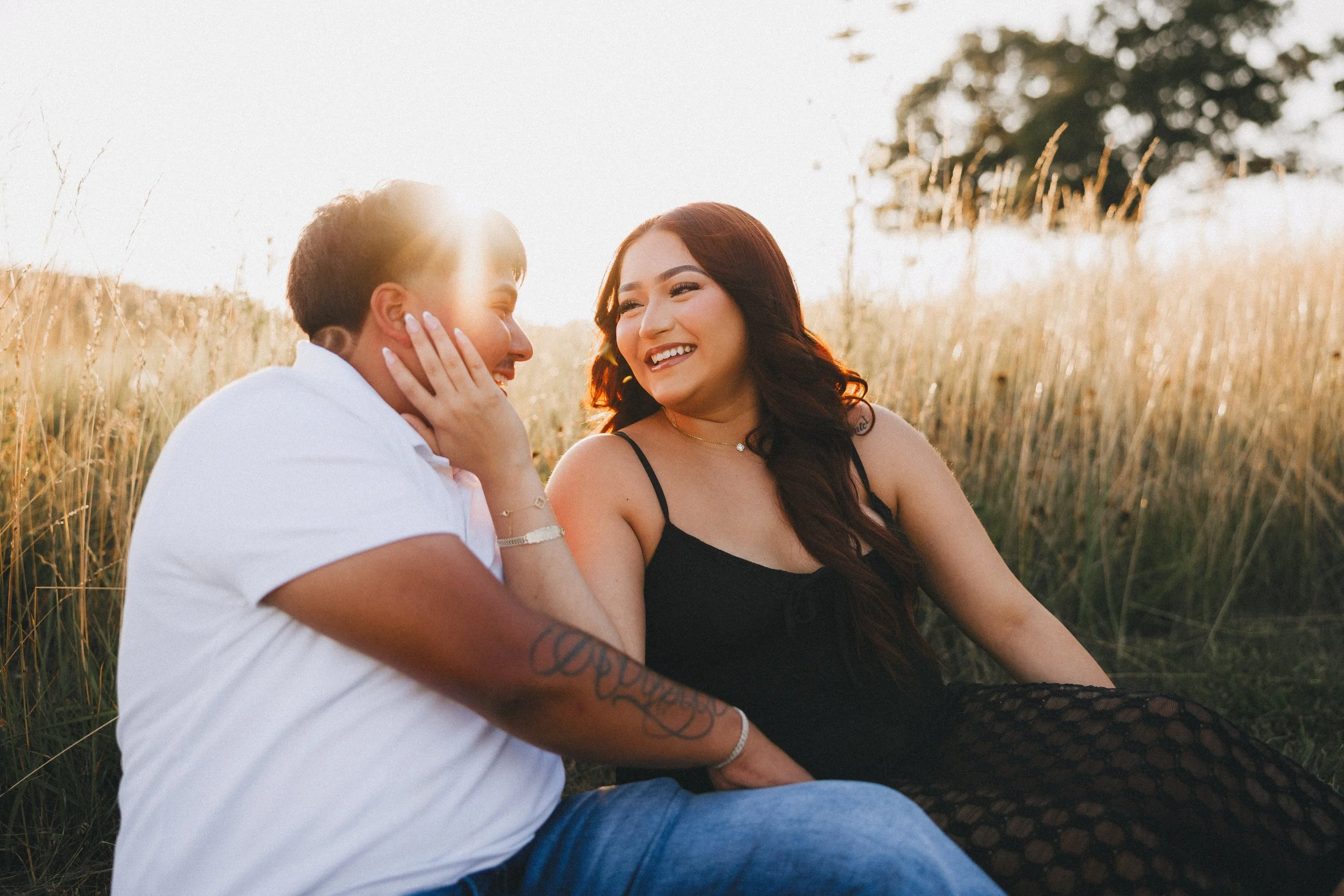 Two women sitting outdoors in a grassy field during sunset, smiling and engaging in conversation.  Shot in Topeka, Kansas. 