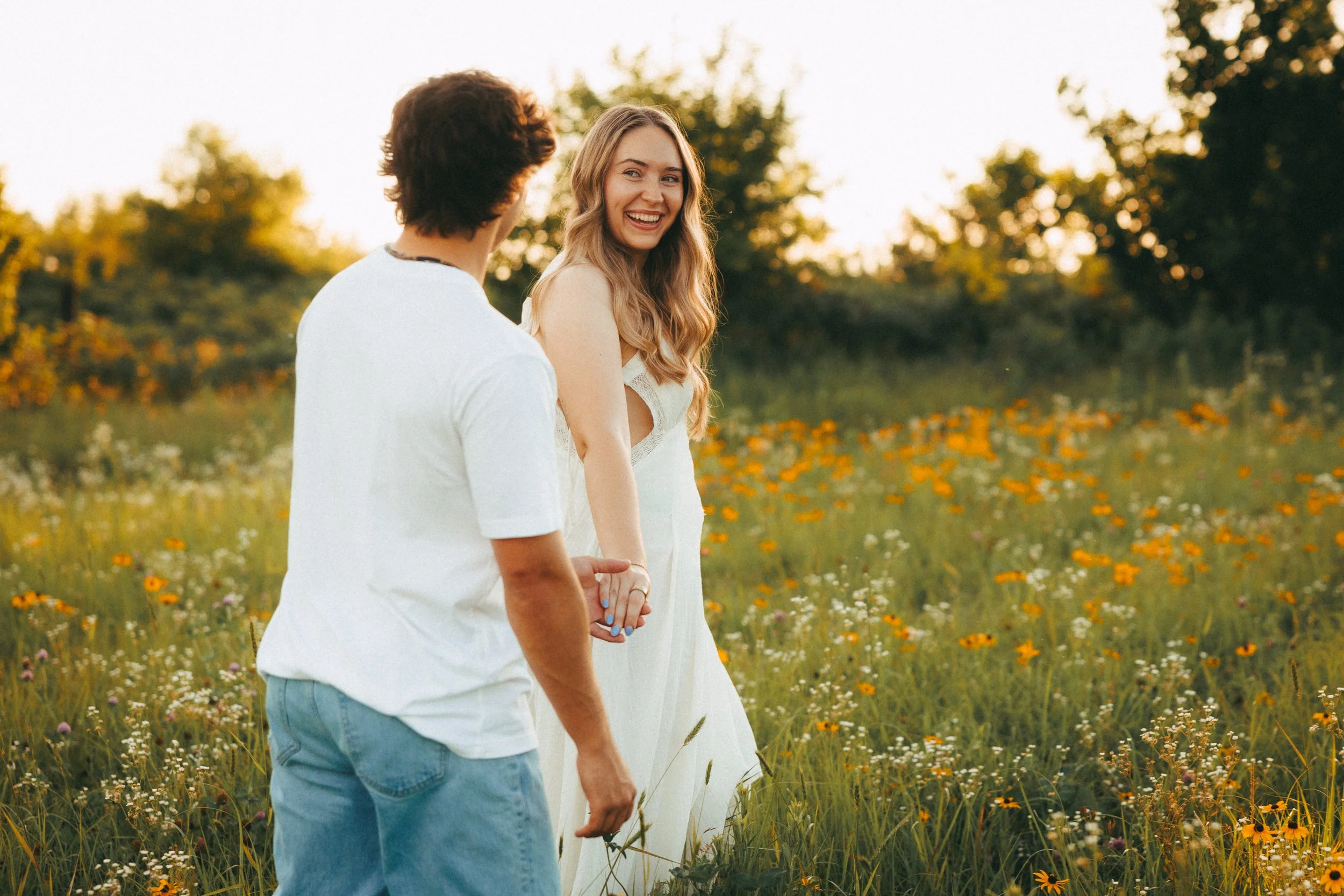 A young couple in a big green field outside of Cedar Lawn Farm in Topeka, Kansas. 