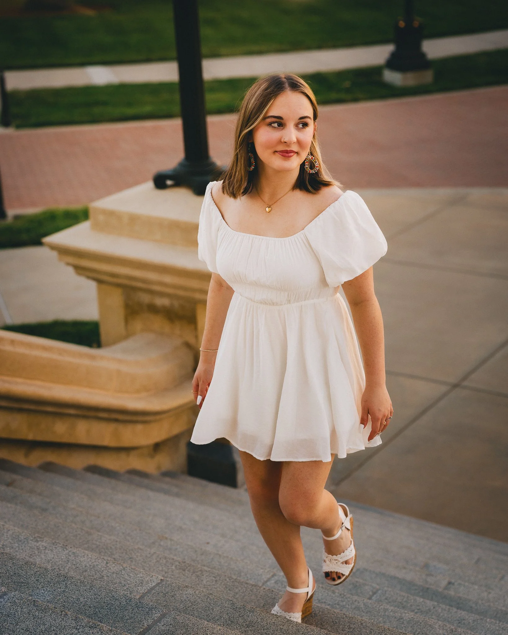 Young woman in a white dress and wedge sandals walking down outdoor steps. Shot in Topeka, Kansas. 