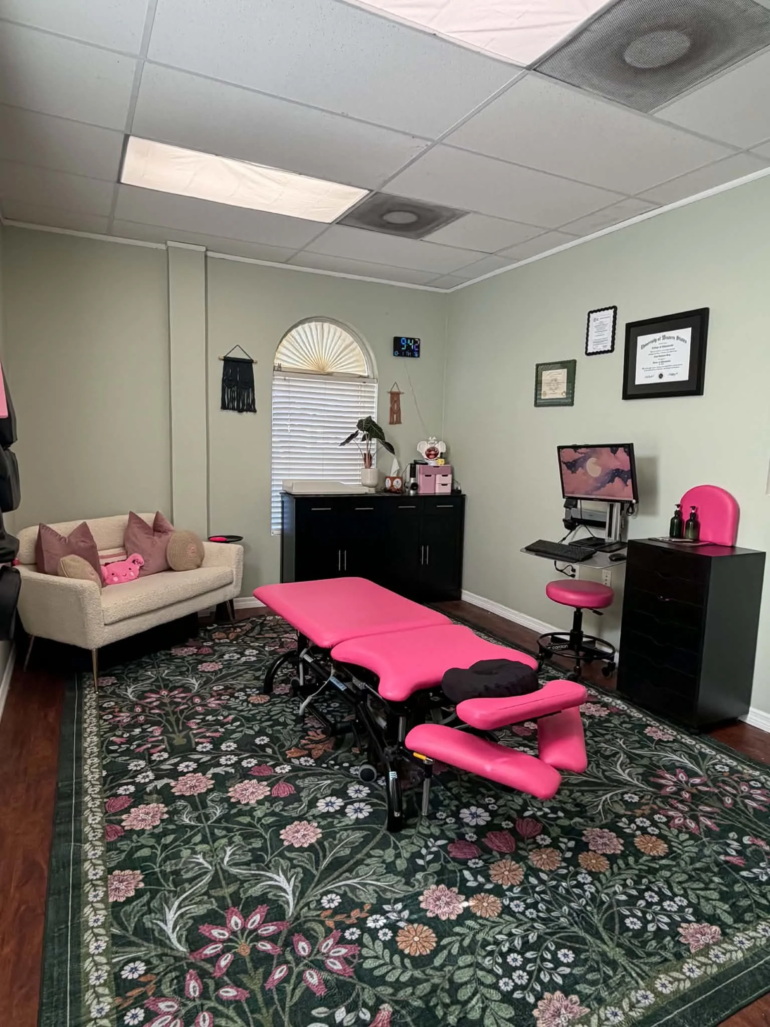 Pink massage table in a room with a small rug and a mirror on the wall.
