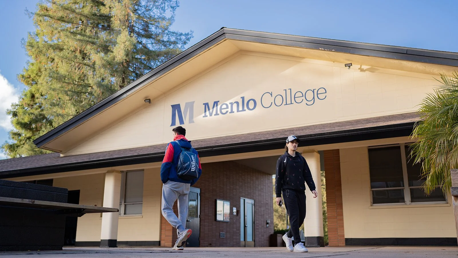 Exterior view of Menlo College building with students walking by.