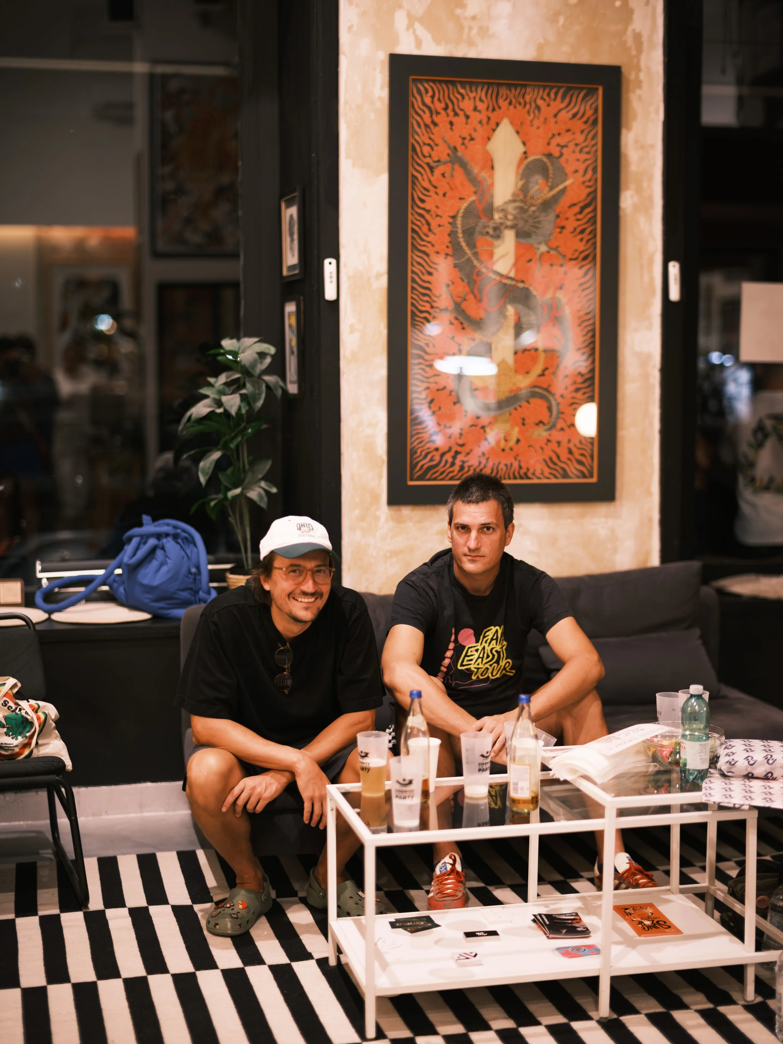 Photograph of three people sitting together in a cozy indoor setting, with a record player partially visible in the foreground.