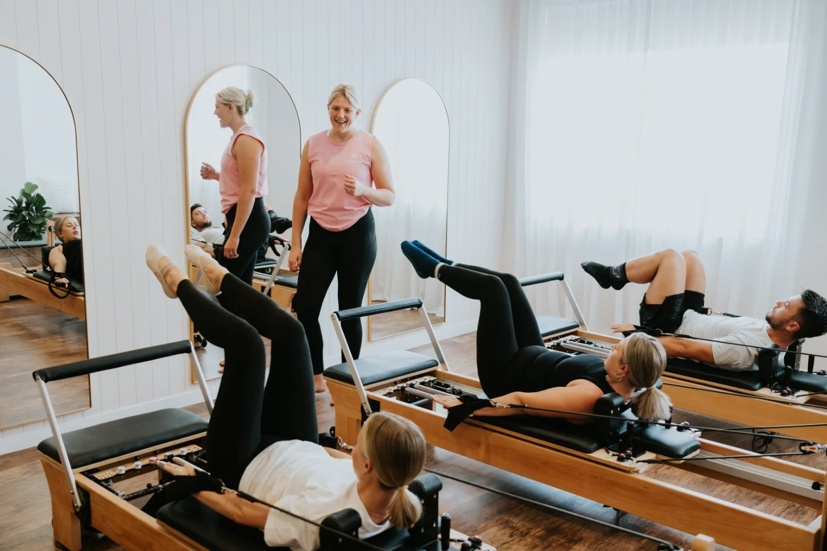 A reformer Pilates teacher at Antara Studios smiles while instructing the room