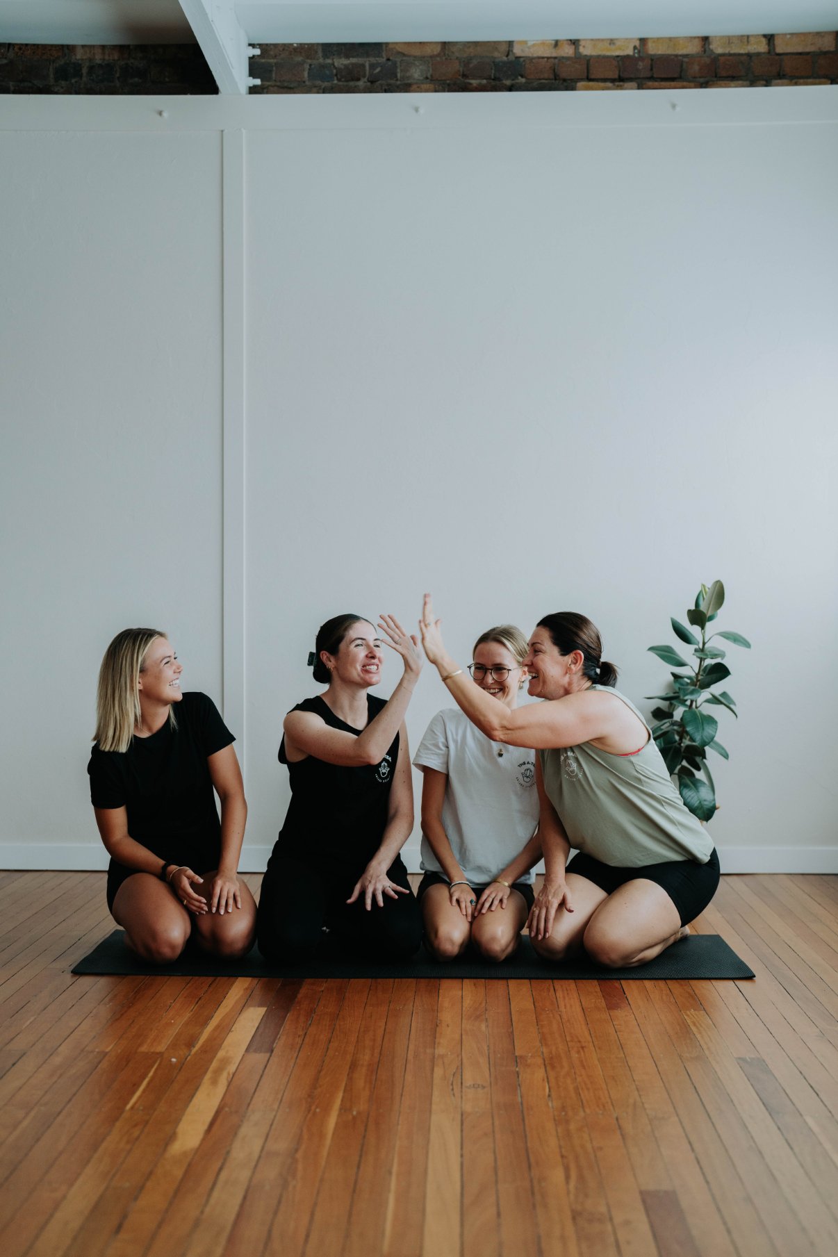 A group of students and teachers smiling and high-fiving together while on a mat at Antara Studios