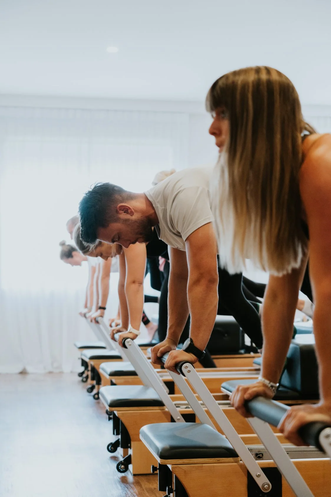 A group of people participating in a reformer Pilates class at Antara Studios