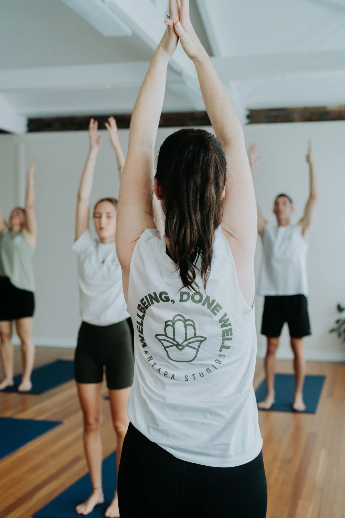 A group of students being warmly guided by a teacher at a mat Pilates class at Antara Studios
