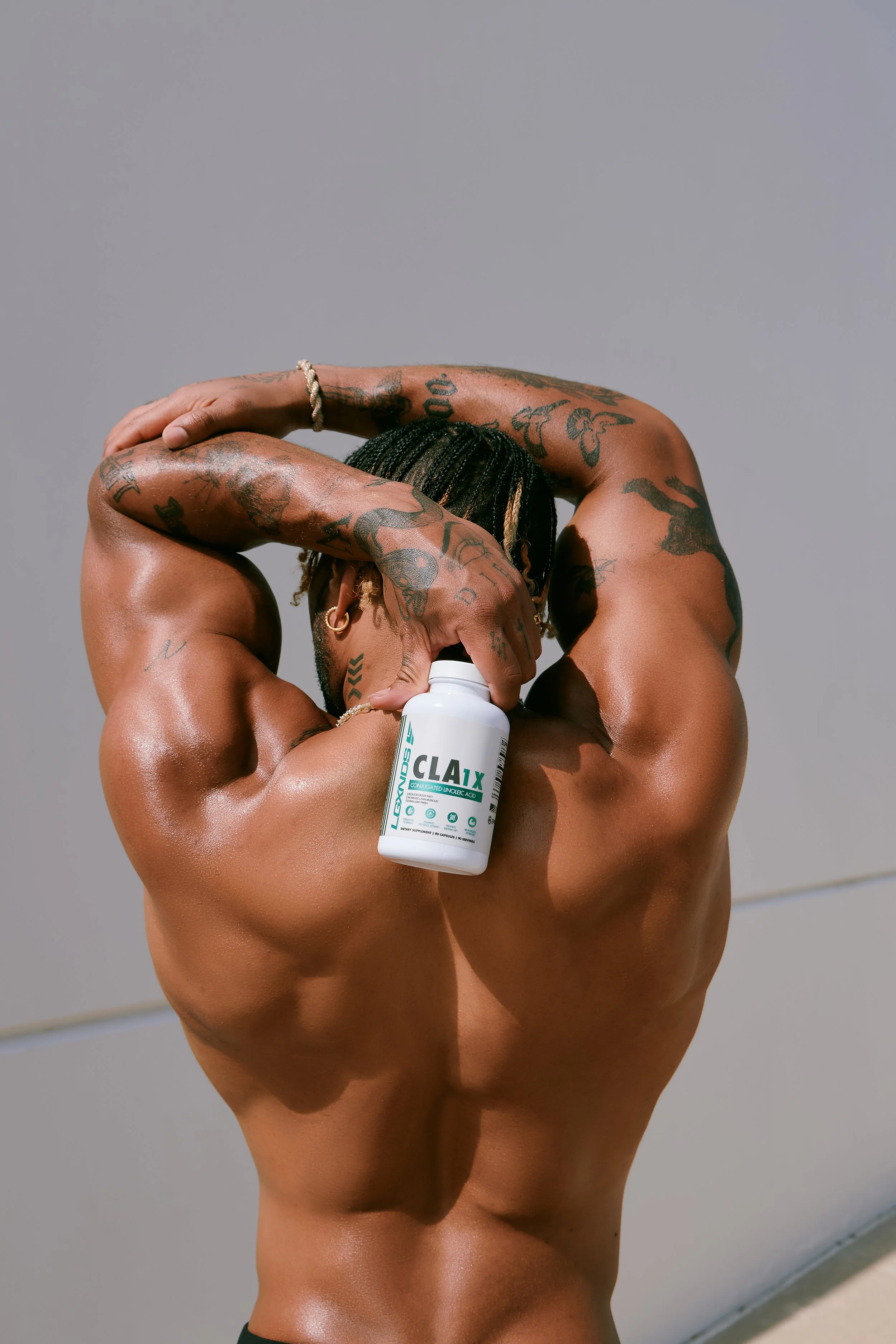 Fitness product campaign image shot in Los Angeles featuring supplement bottle with athletic model in studio lighting