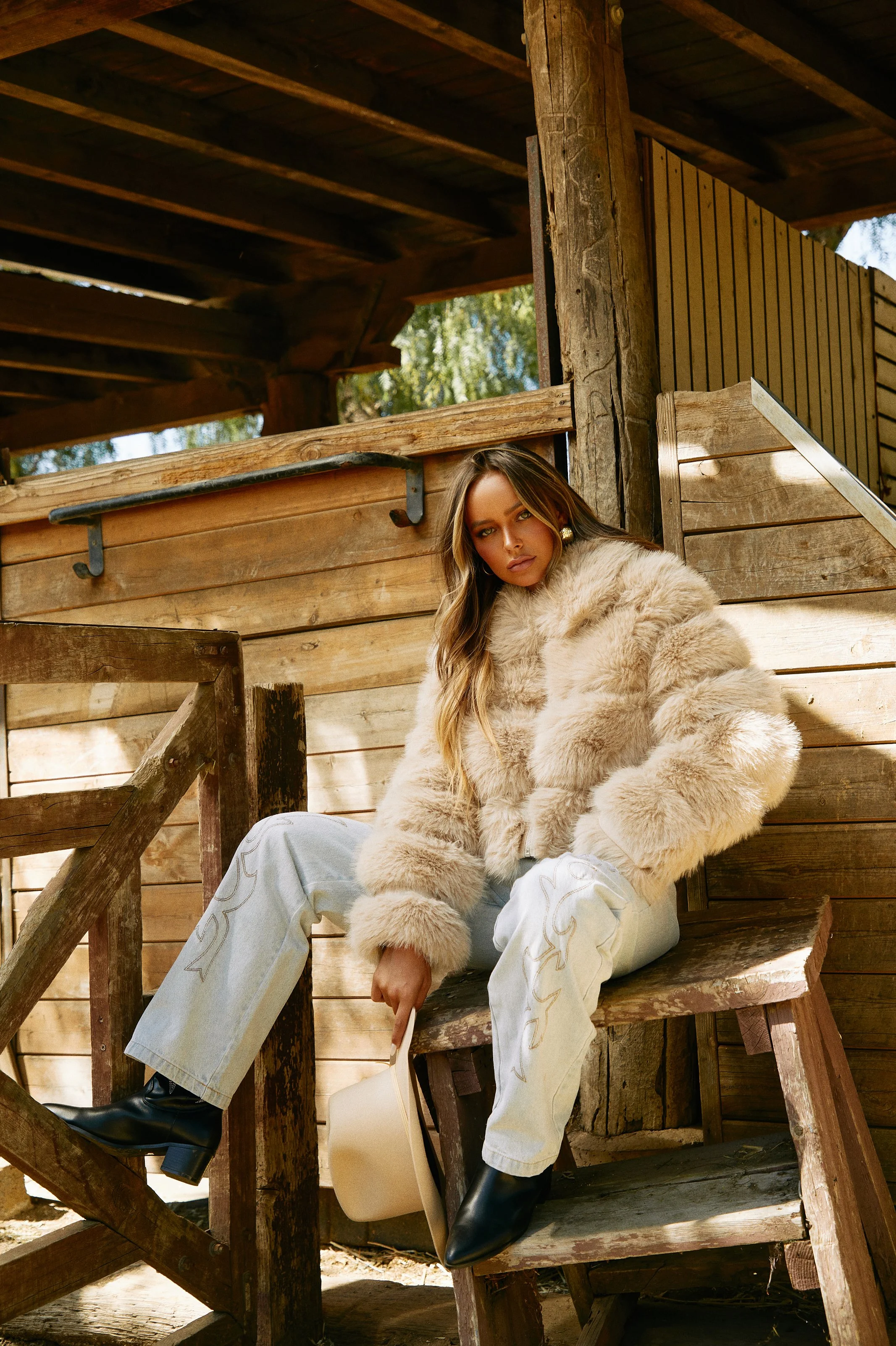 Fashion photography in Los Angeles: cream faux-fur coat and jeans on a rustic wooden porch, by Moises Martinez