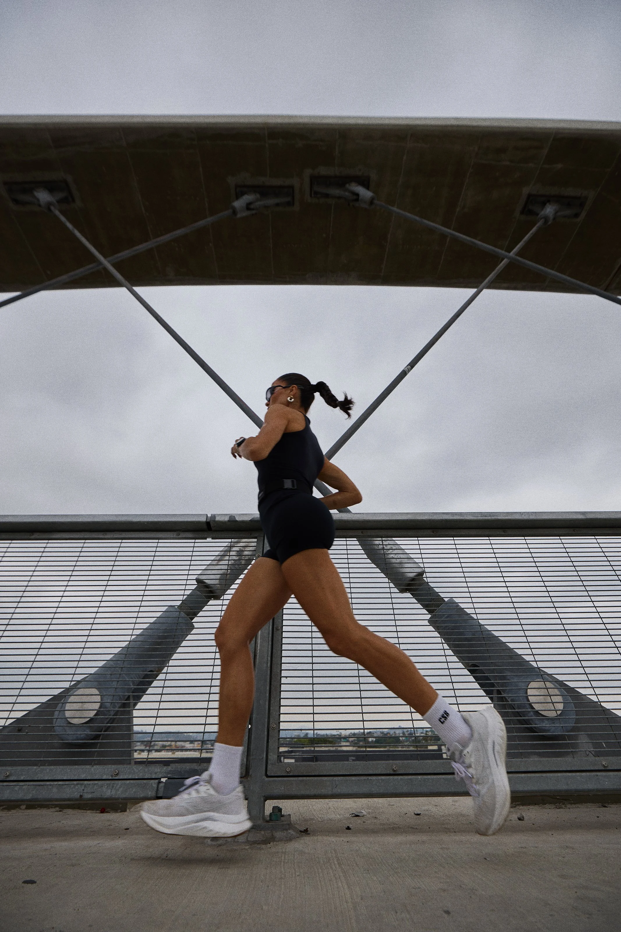 Activewear photography in Los Angeles: runner in black activewear crossing a bridge, by Moises Martinez