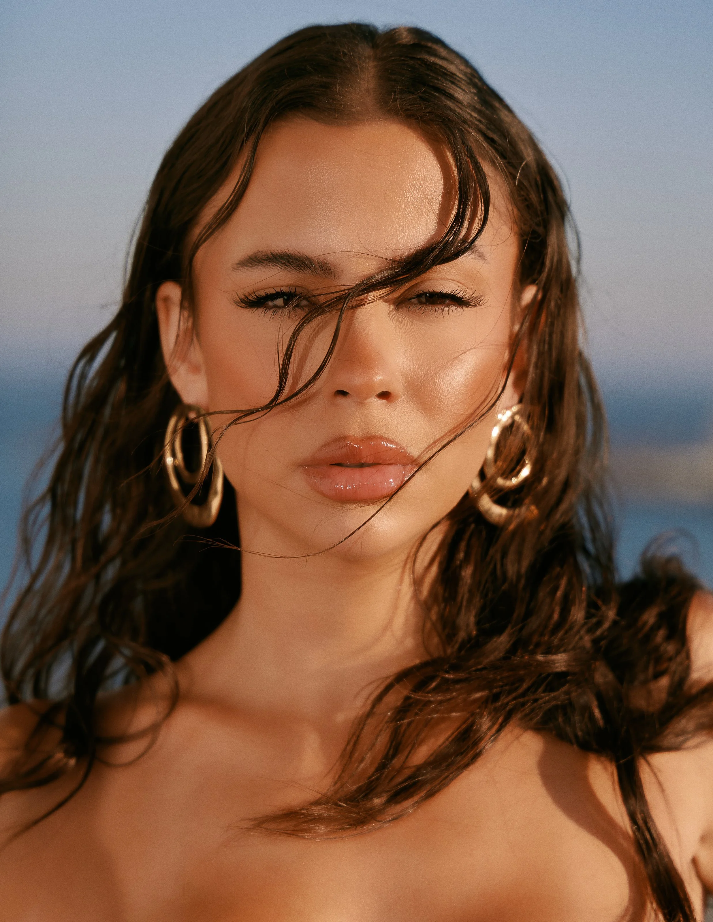 Fashion photography in Los Angeles: close portrait with windswept hair and gold hoop earrings, by Moises Martinez