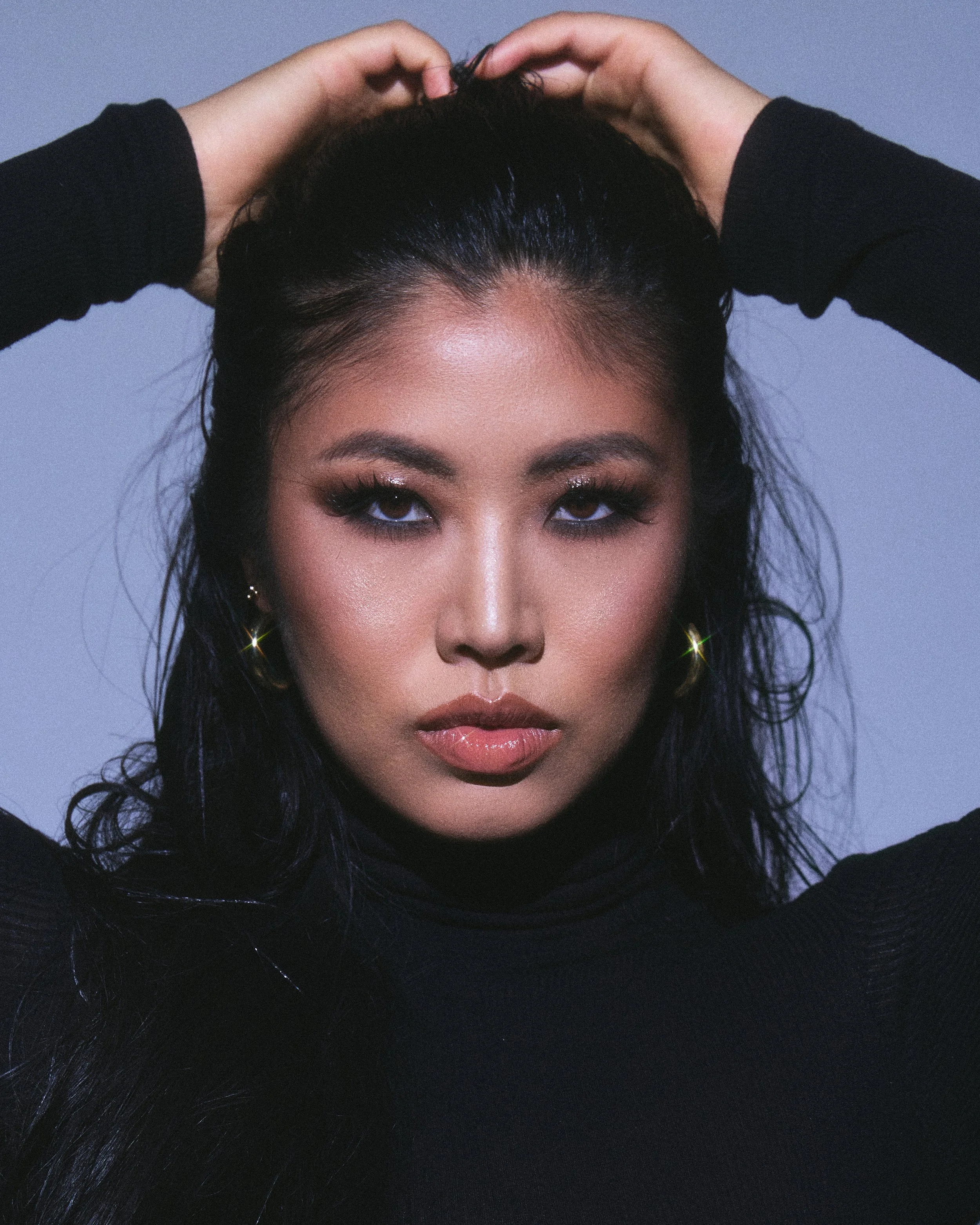 Beauty photography in Los Angeles: hands in wet-look hair, smoky glam on blue, by Moises Martinez