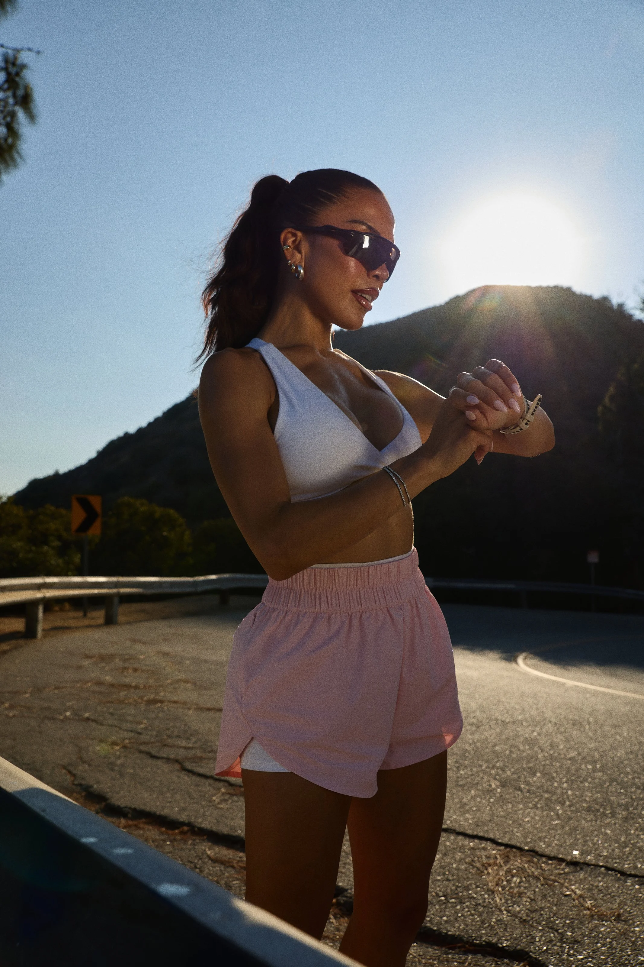 Activewear photography in Los Angeles: pink set and white top on a hillside road at sunset, by Moises Martinez