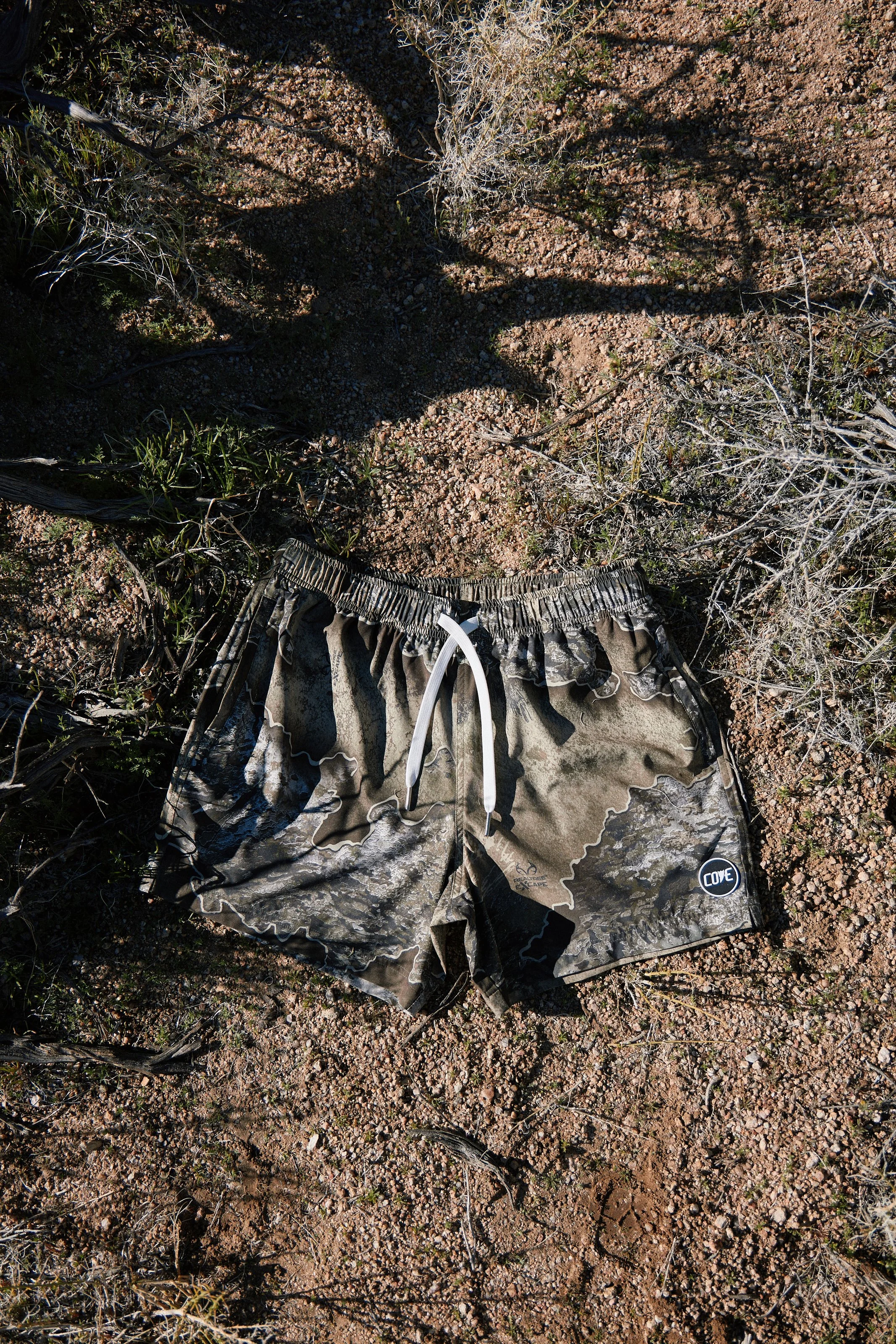 Activewear photography in Los Angeles: camo shorts laid flat on desert rocks, by Moises Martinez