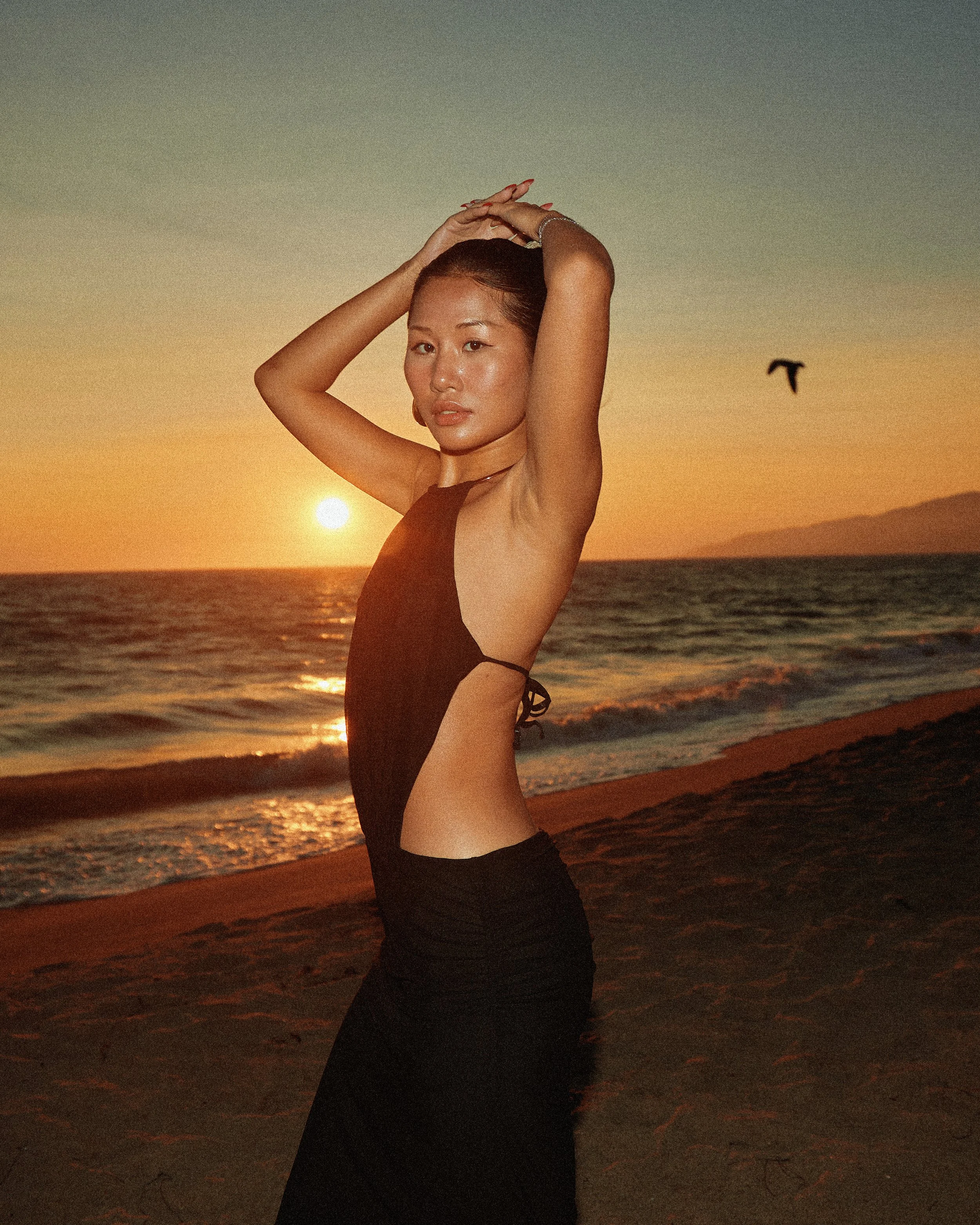 Fashion photography in Los Angeles: black backless dress silhouetted at sunset on the beach, by Moises Martinez
