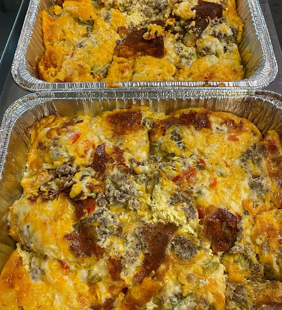 Two foil trays of cheesy breakfast casserole with sausage and vegetables.