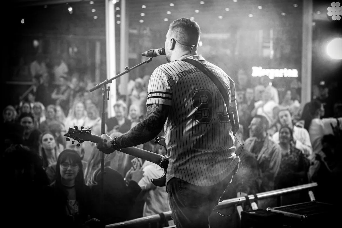 Sångaren från Dunderklubben coverband står på scen framför en entusiastisk publik på Frimis i Örebro, iförd randig tröja med nummer 93 på ryggen.