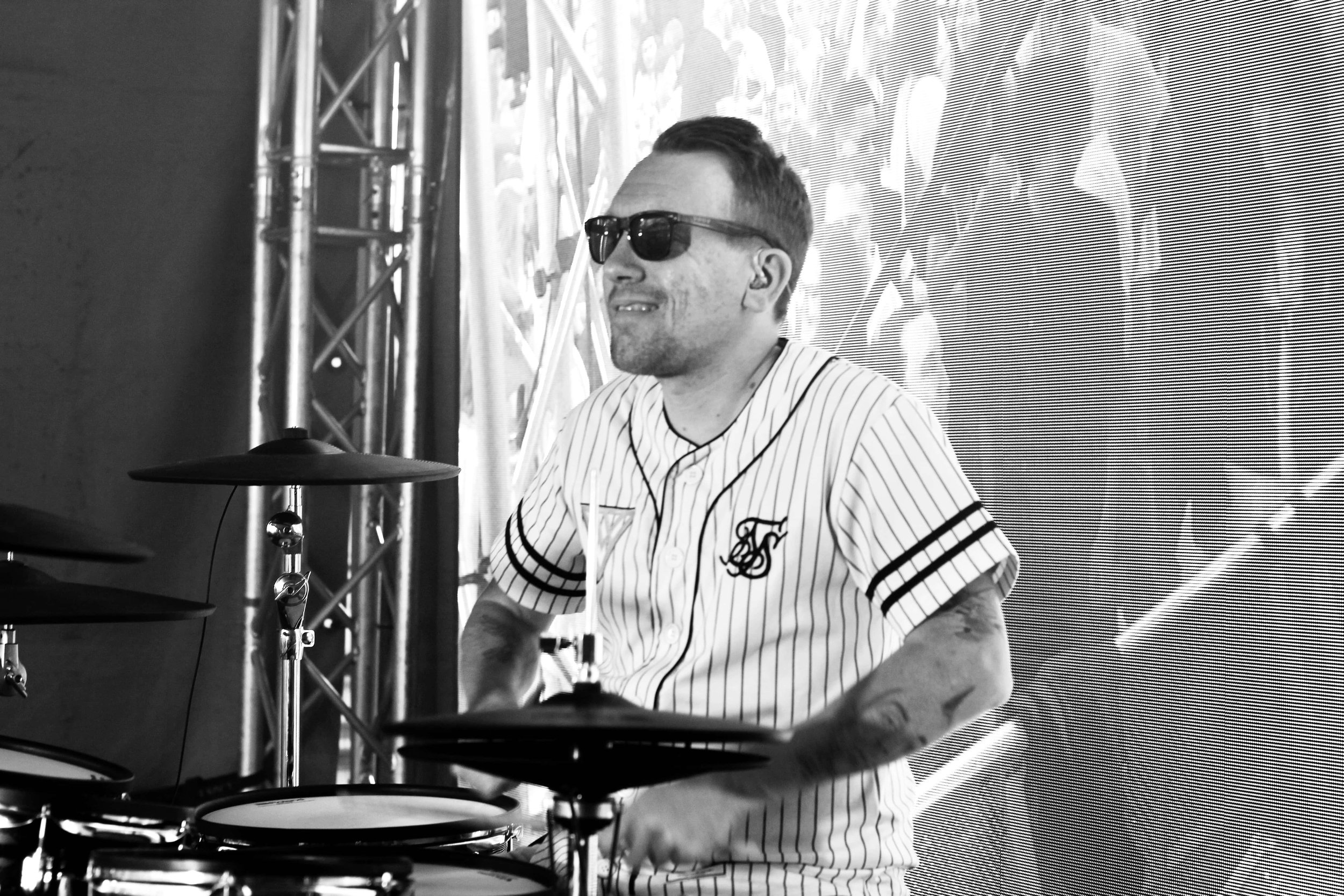 Manlig kortklippt trummis i solglasögon spelar på digitala trummor.