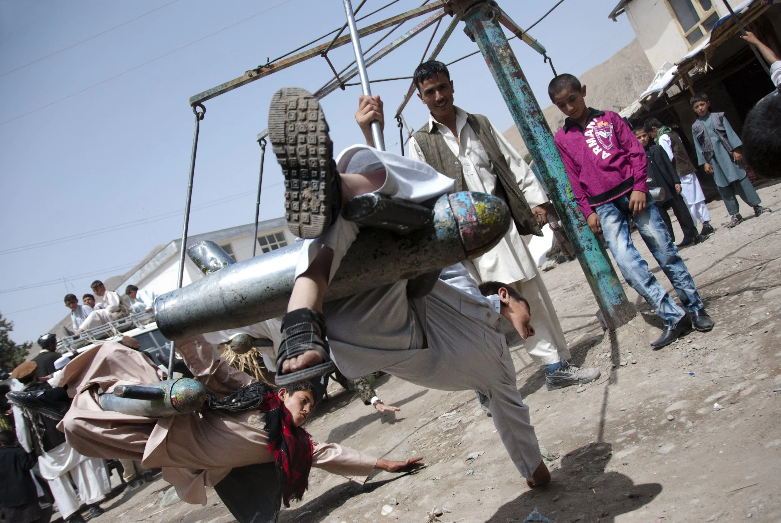 Post-war games, Faizabad 2011 A carrousel is constructed from used bomb shells with children sitting and playing on it. It’s Eid, the end of Ramadan. A time of family and time of joy. Everybody comes to have a ride on carousel and for a while to forg